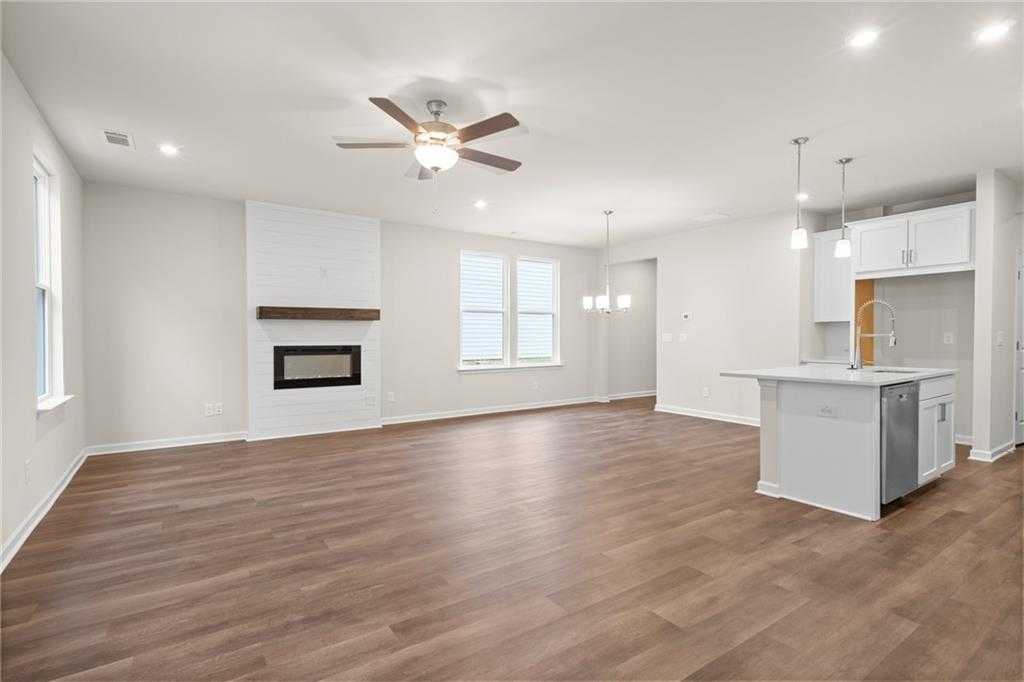 Spacious open-concept living room with modern fireplace, ceiling fan, and kitchen island in Davidson Homes The Marion B, Kennesaw, GA