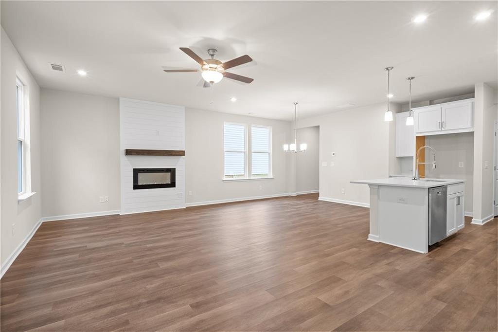 Spacious open-concept living room with modern fireplace, ceiling fan, and kitchen island in Davidson Homes The Marion B, Kennesaw, GA