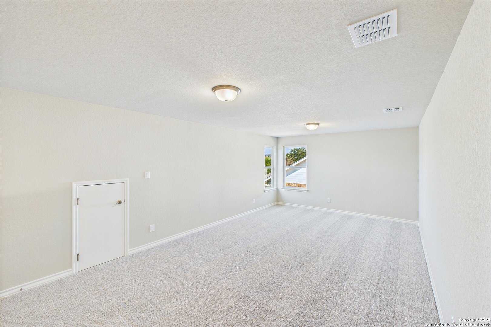 Empty bedroom with beige walls, berber carpet, recessed lighting, and window in 5-bedroom Davidson Homes The Jennings H, Ladera, San Antonio