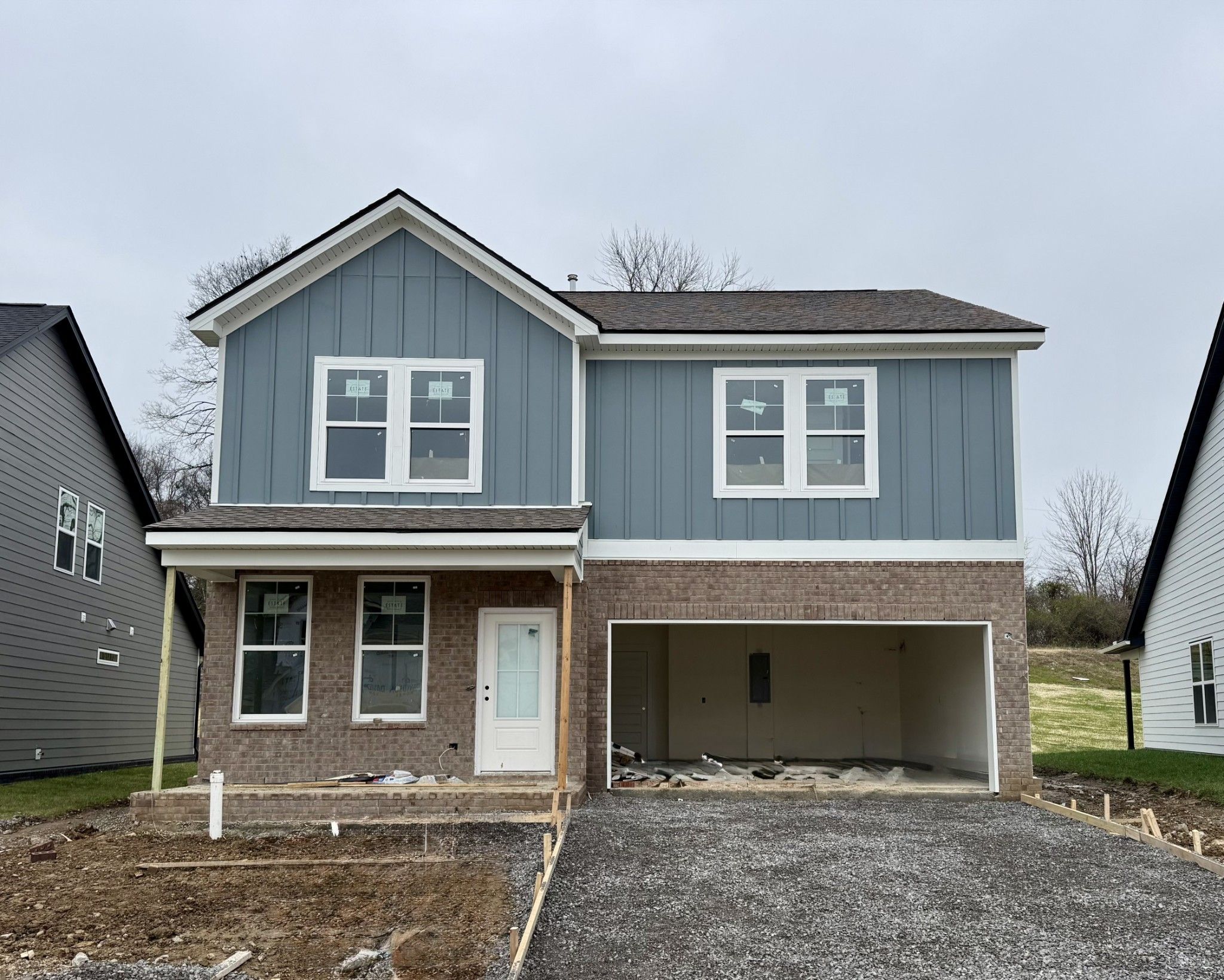 Two-story blue home with gabled roof, 2-car brick garage, front porch in Woods Crossing, Gallatin, Tennessee - Davidson Homes Logan C