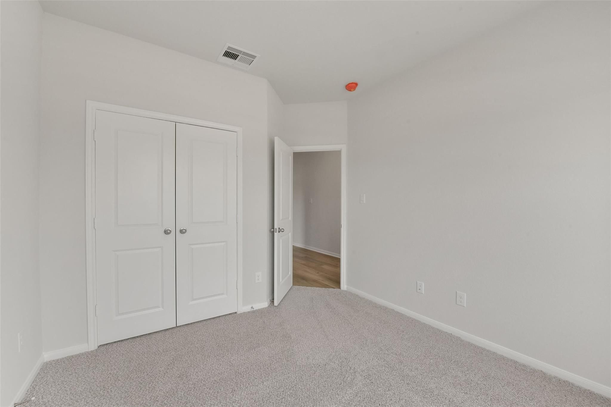 Bright secondary bedroom with double closet doors and adjacent bath entry in Davidson Homes Laguna B, Magnolia TX