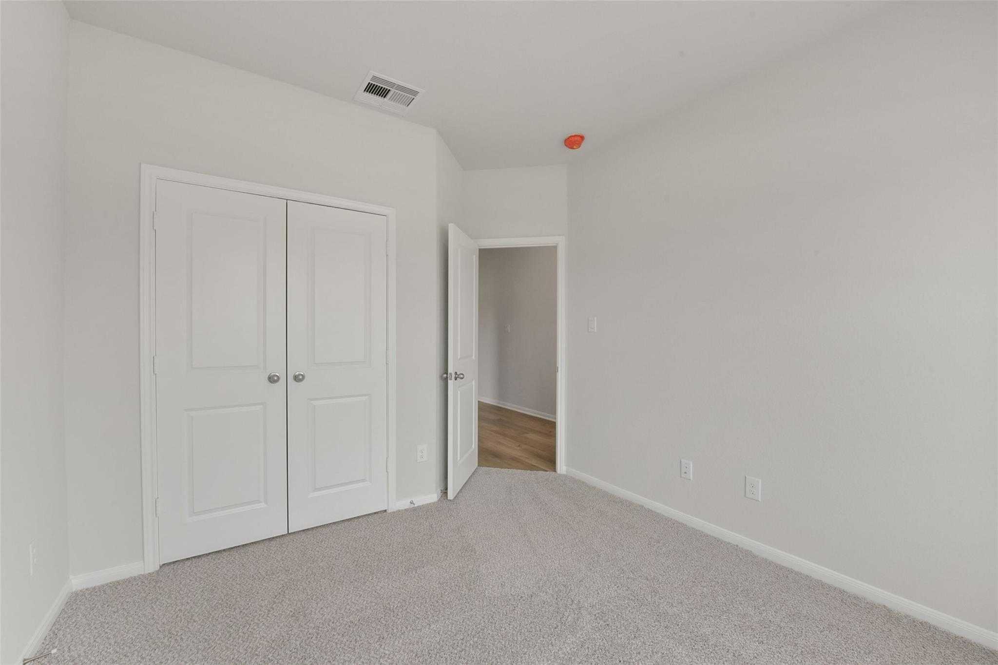 Bright secondary bedroom with double closet doors and adjacent bath entry in Davidson Homes Laguna B, Magnolia TX