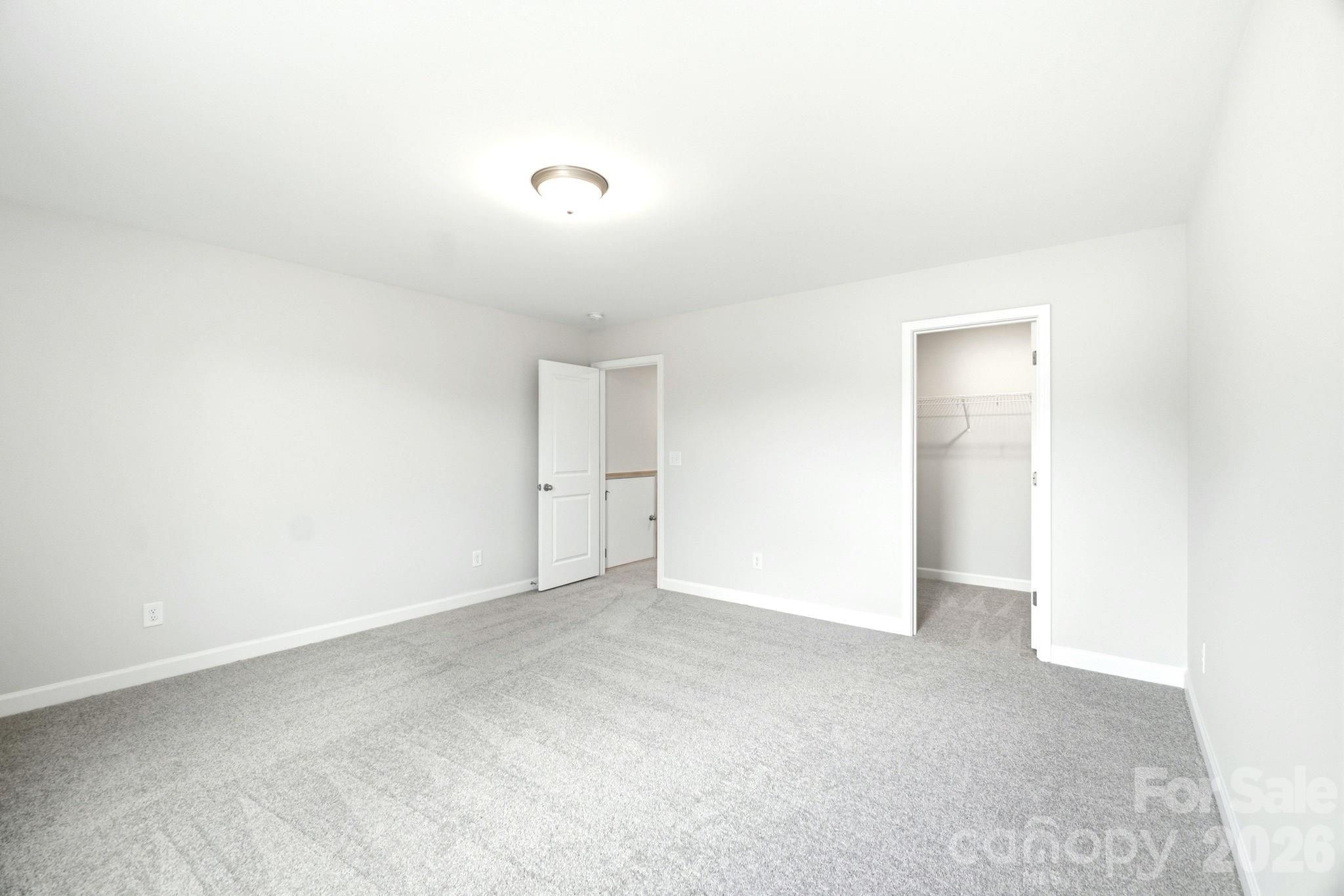 Bright, carpeted bedroom with walk-in closet in The Magnolia B floor plan at Windgate, Mooresville, North Carolina.