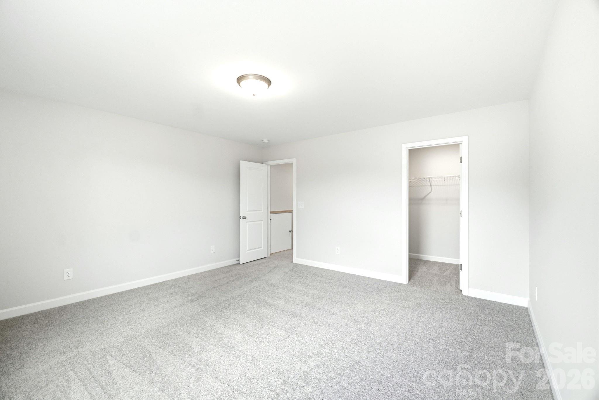 Bright, carpeted bedroom with walk-in closet in The Magnolia B floor plan at Windgate, Mooresville, North Carolina.
