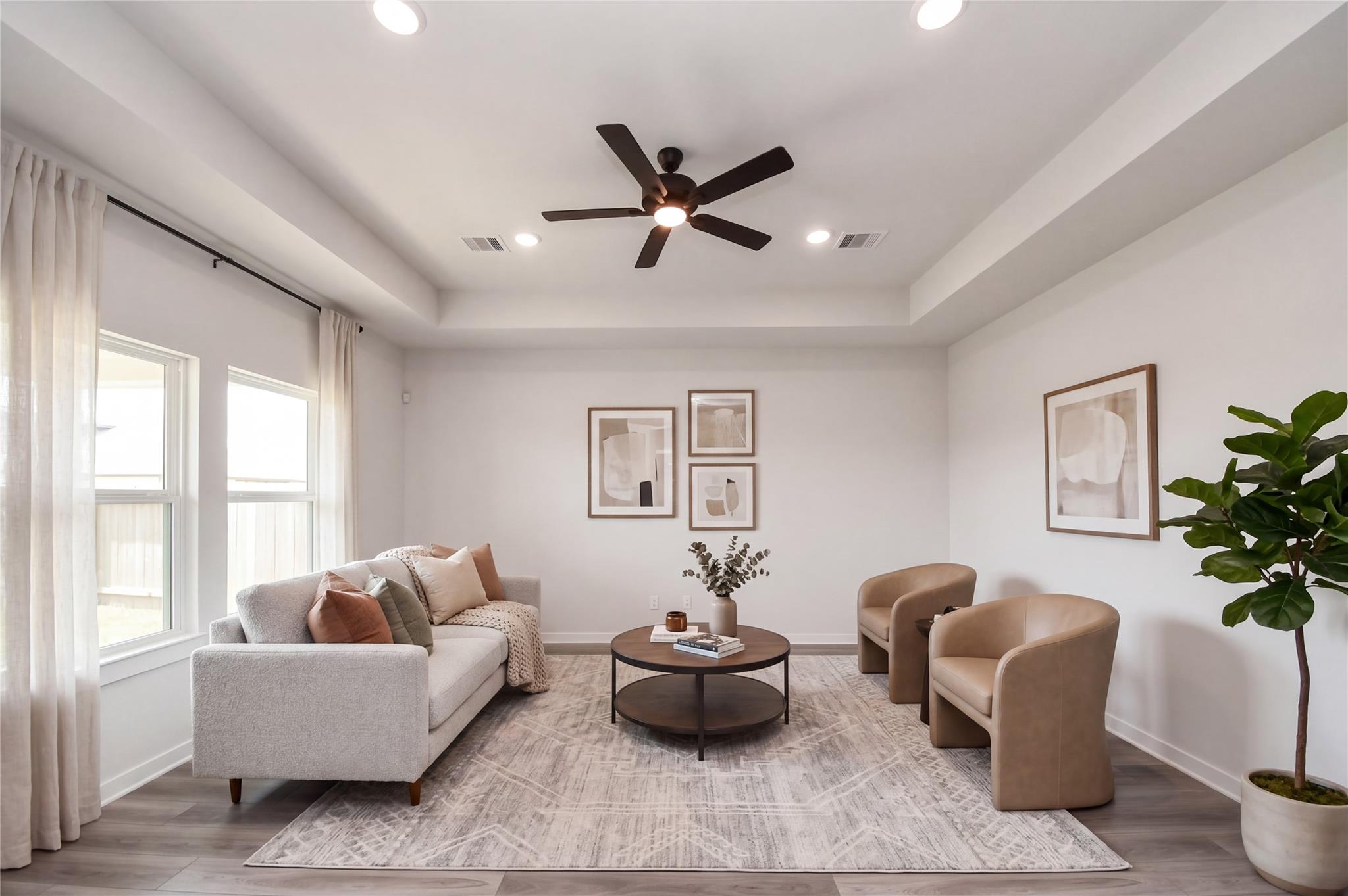 Bright, modern living room with tray ceiling in The Everett C floor plan at River Ranch Meadows, Dayton, Texas.