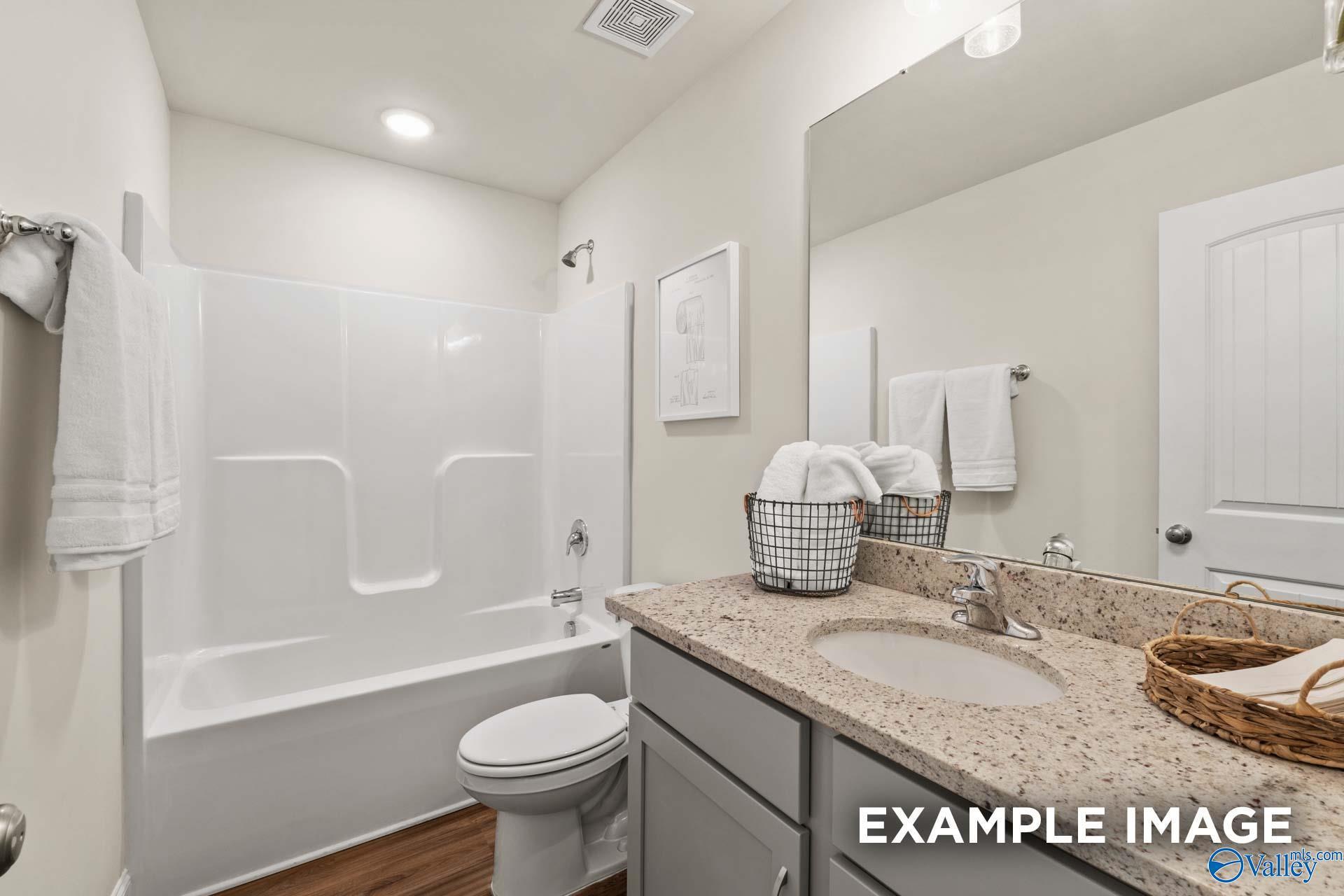 Bright secondary bathroom with tub-shower combo, granite vanity, single sink, and towel storage in Davidson Homes The Franklin C, New Market, Alabama
