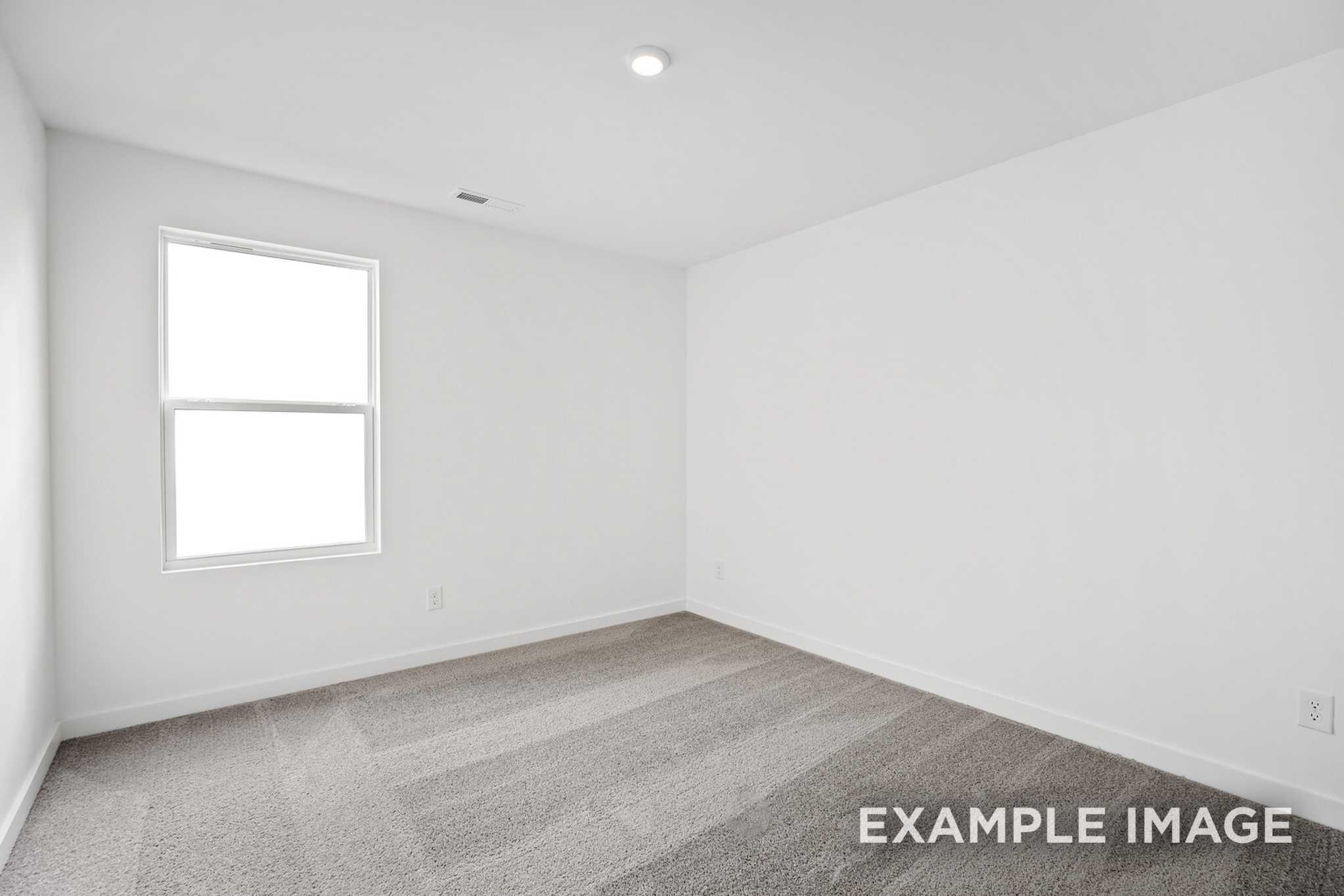 Spacious empty bedroom in The Murray B home plan with white walls, large window, and gray carpet flooring