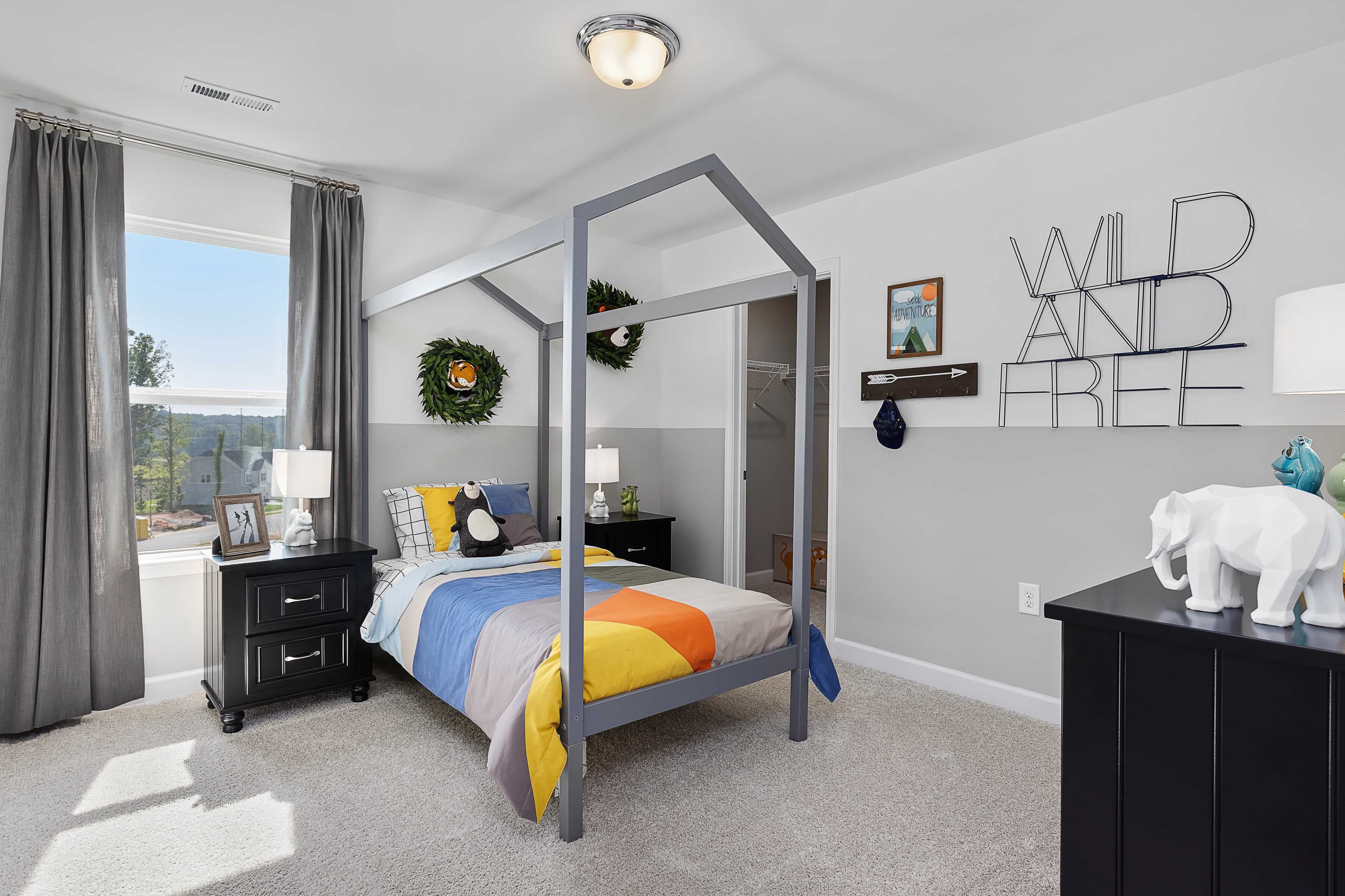 Playful child's bedroom with colorful canopy bed and "Wild and Free" wall decor at Woodland Crossing in Zebulon NC