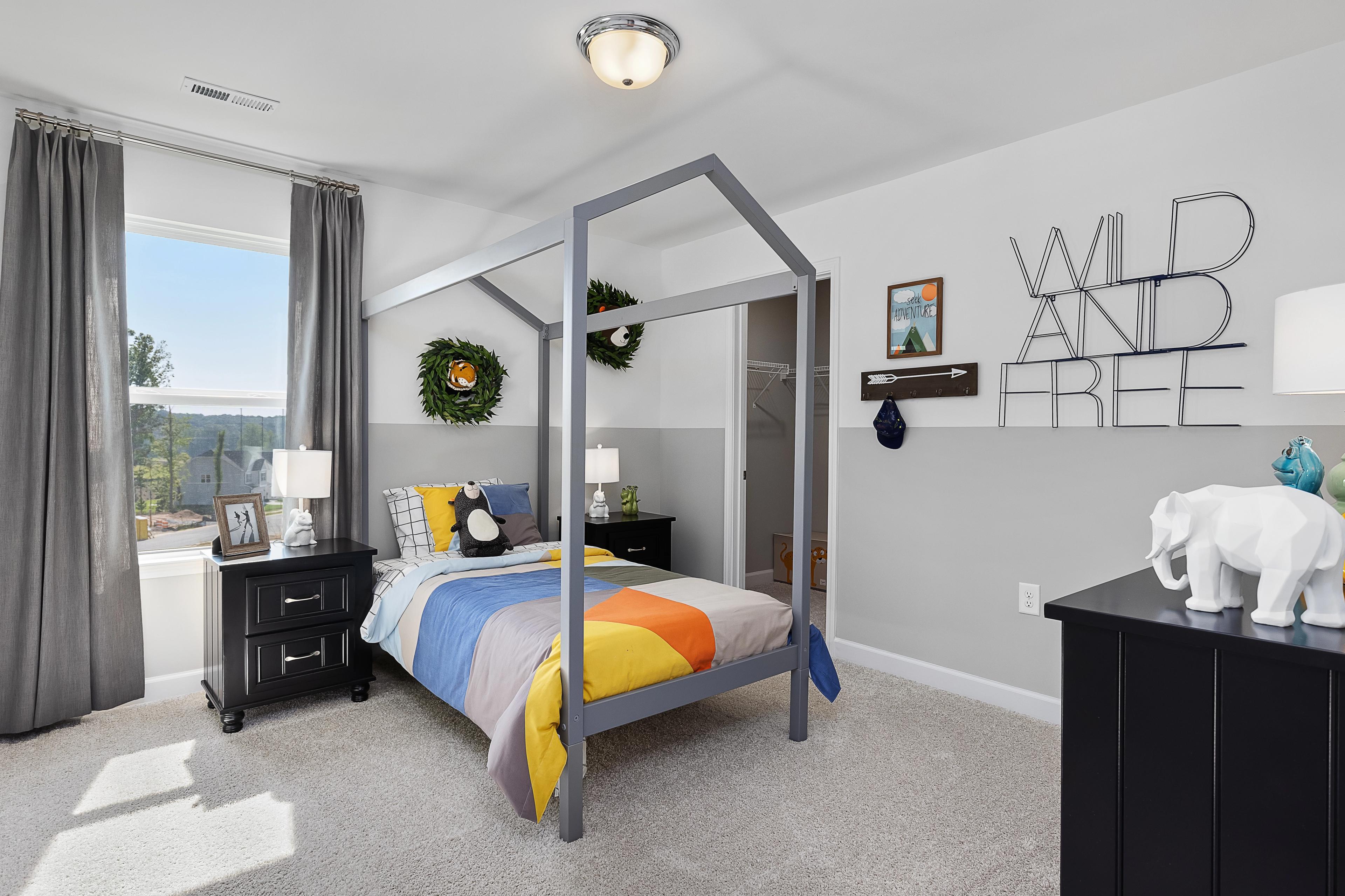 Playful child's bedroom with colorful canopy bed and "Wild and Free" wall decor at Woodland Crossing in Zebulon NC