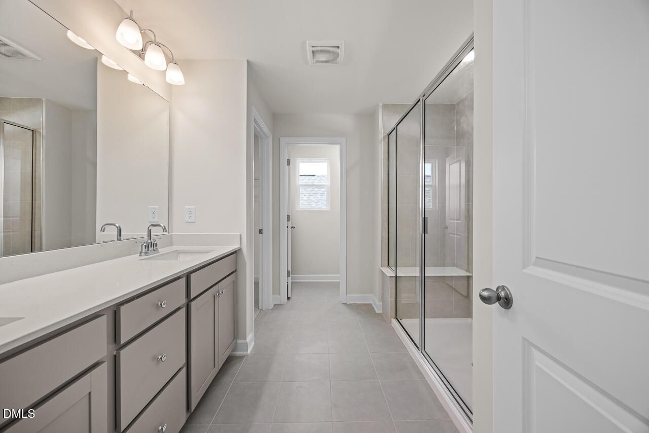 Modern primary bathroom with double vanity and glass-enclosed shower in The Gavin A plan at Gregory Village, Lillington, NC.