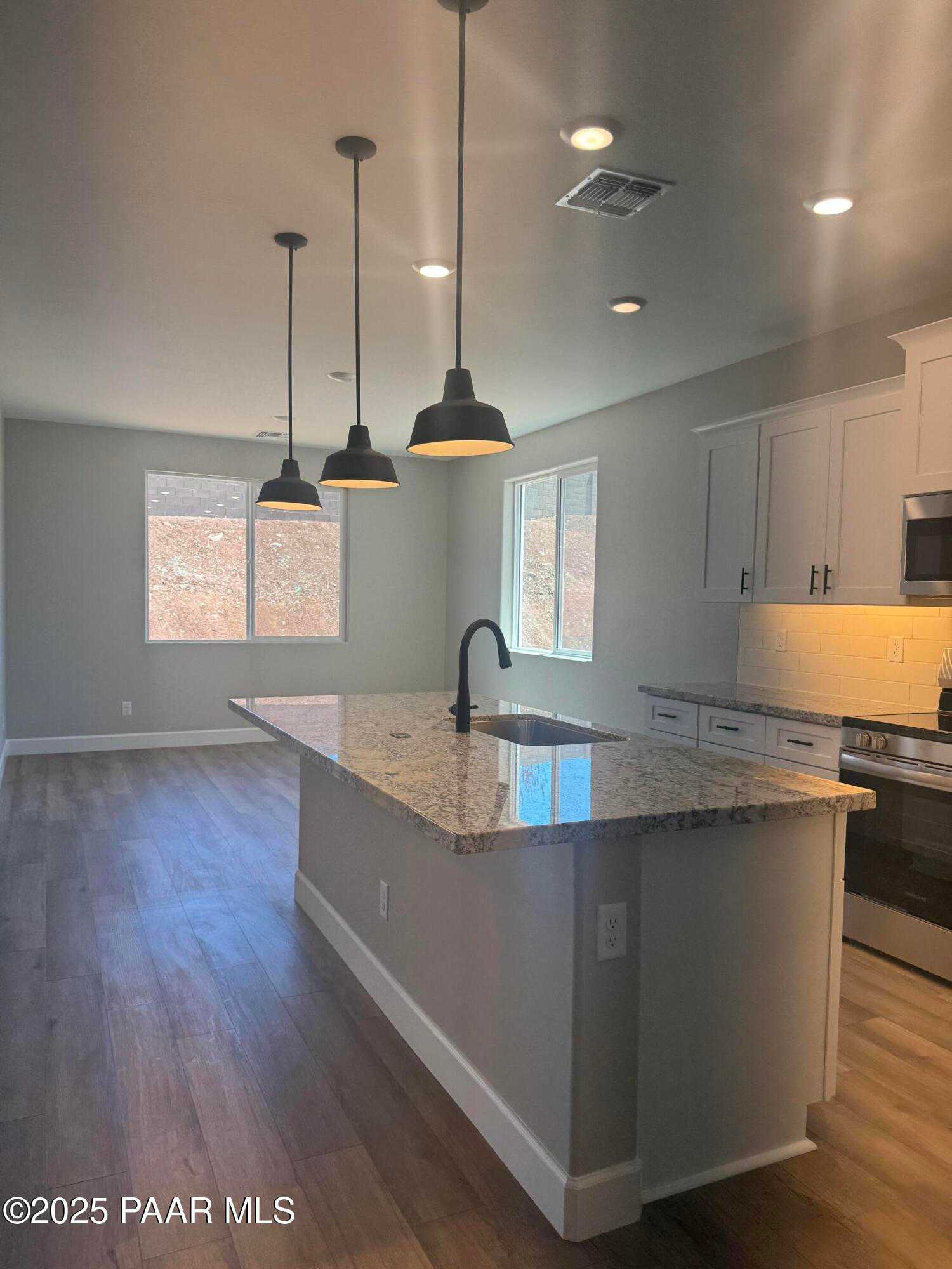 Modern kitchen with granite island, white cabinets, stainless appliances, pendant lights in The Summit B, Prescott Valley, AZ