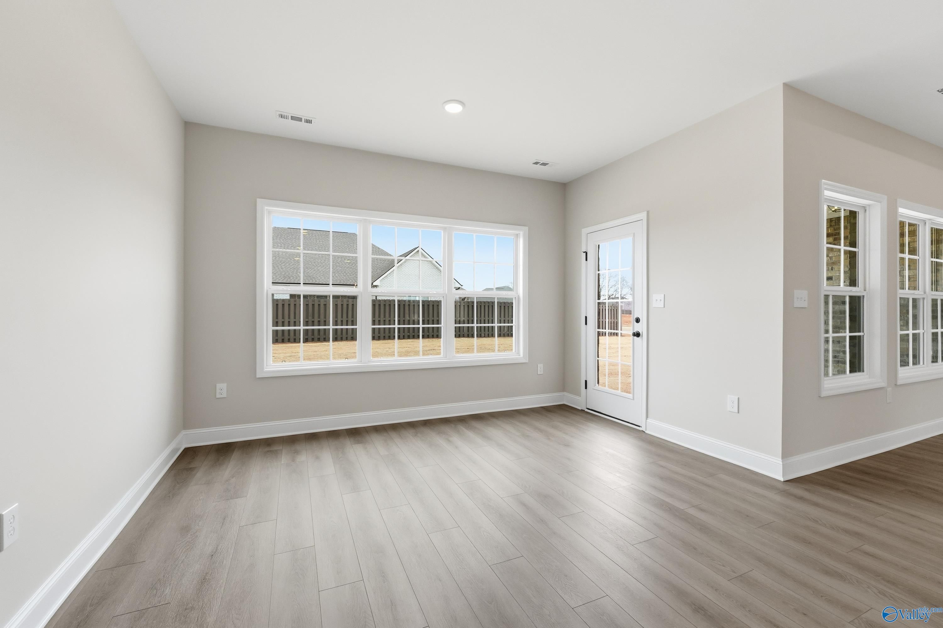 Bright sunroom with large windows, glass door to backyard, light gray walls, and hardwood floors in Davidson Homes The Finleigh, Meridianville, Alabama