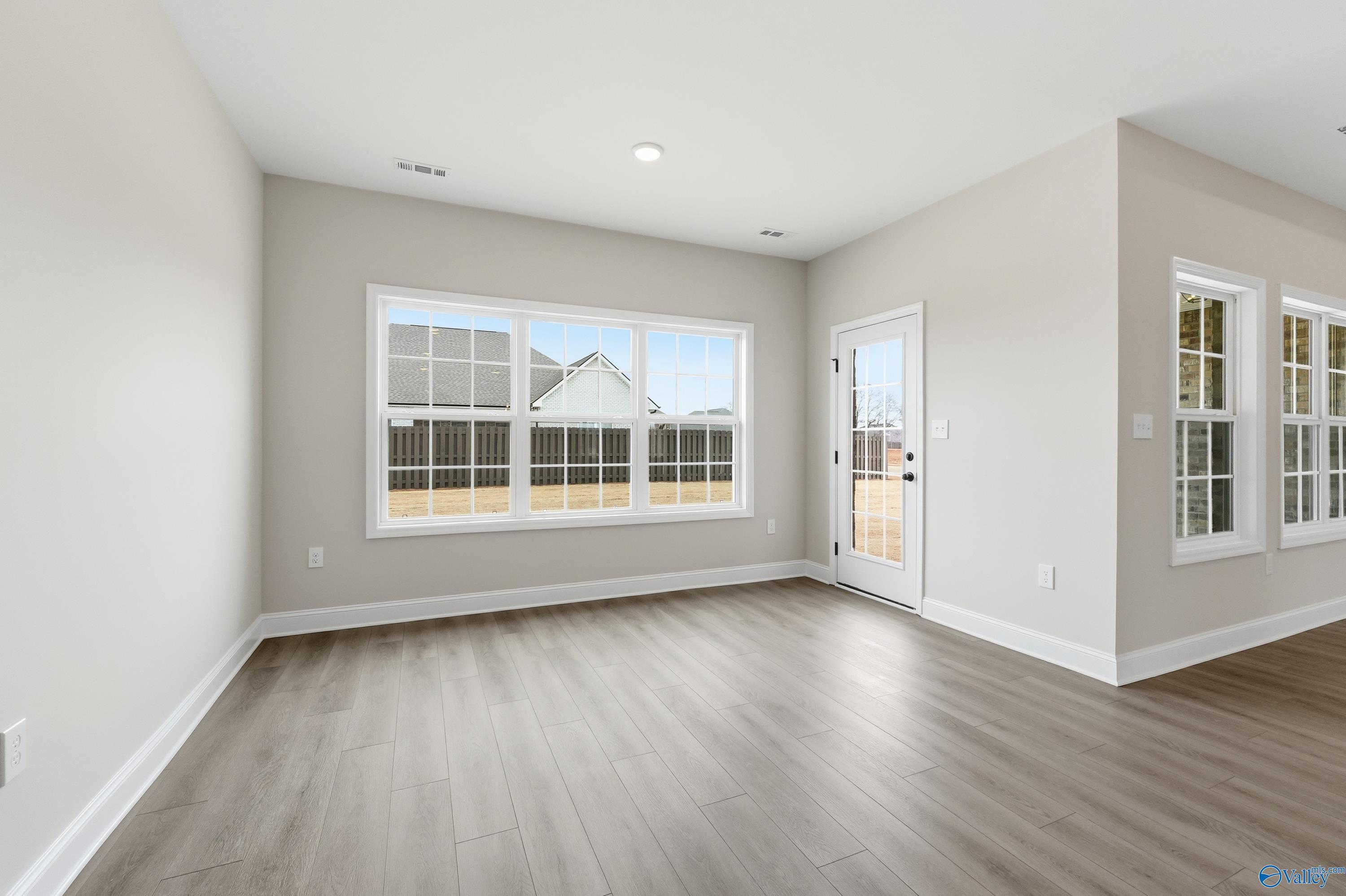 Bright sunroom with large windows, glass door to backyard, light gray walls, and hardwood floors in Davidson Homes The Finleigh, Meridianville, Alabama