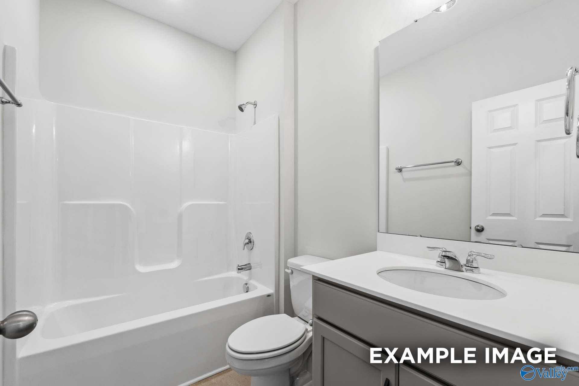 Bright white bathroom with tub-shower combo, vanity sink, and mirror in Davidson Homes The Lanier, Toney Alabama