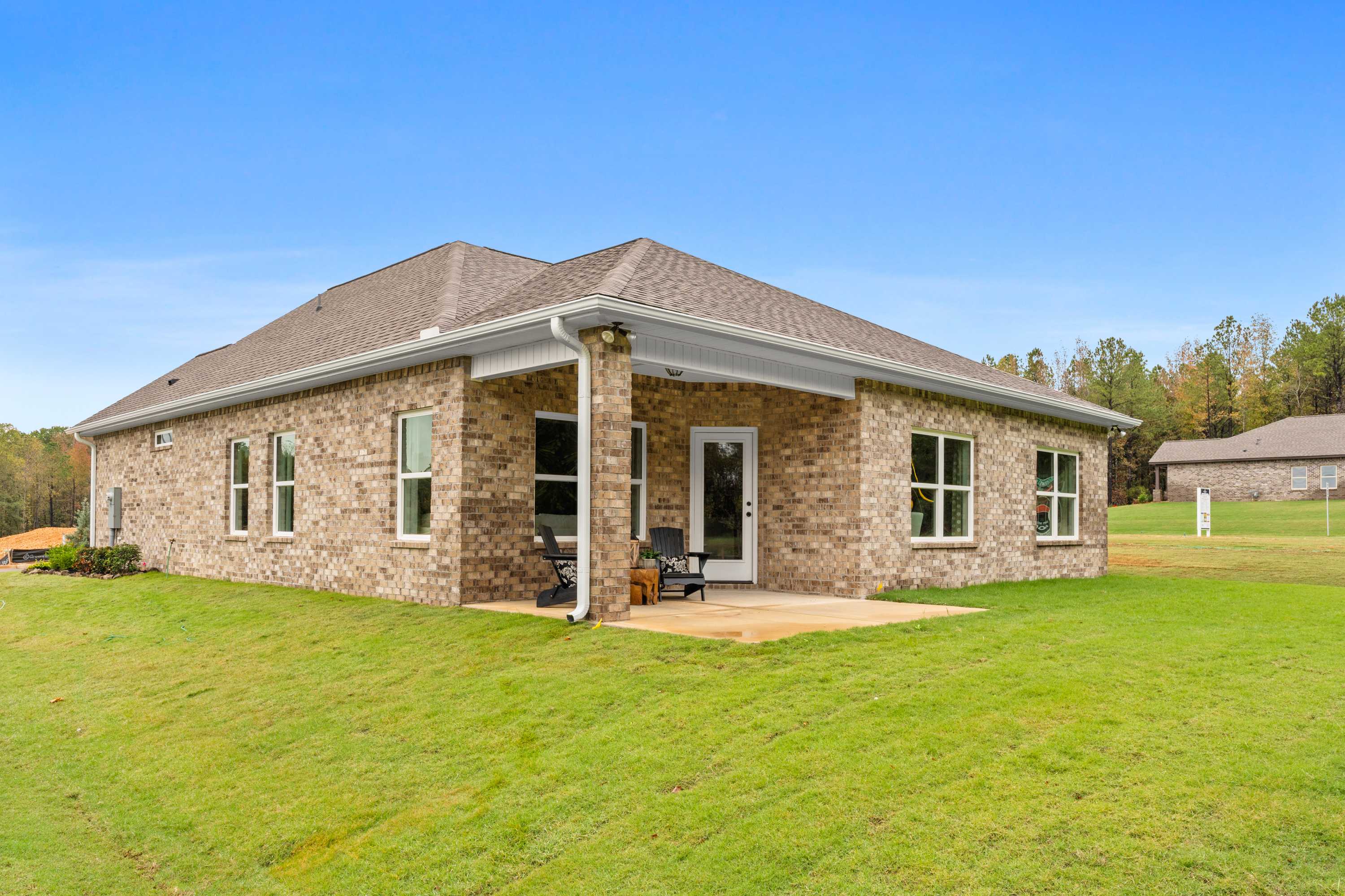 Brick ranch home exterior at Spragins Cove in Huntsville Alabama with covered patio, green lawn, and autumn trees