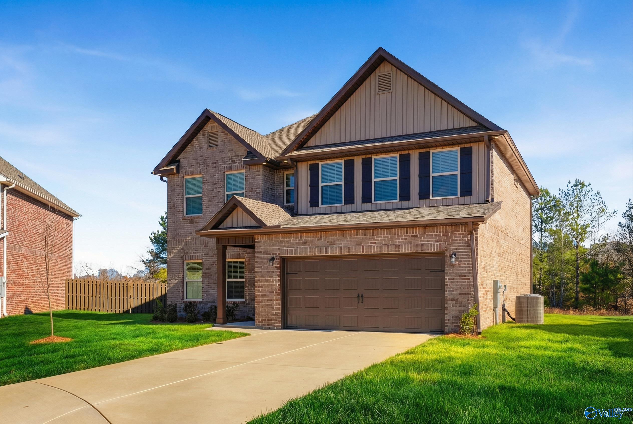 Two-story brick home with gabled roof, 2-car garage, and driveway on green lawn in Ricketts Farm, Athens, Alabama - Davidson Homes The Shelby A