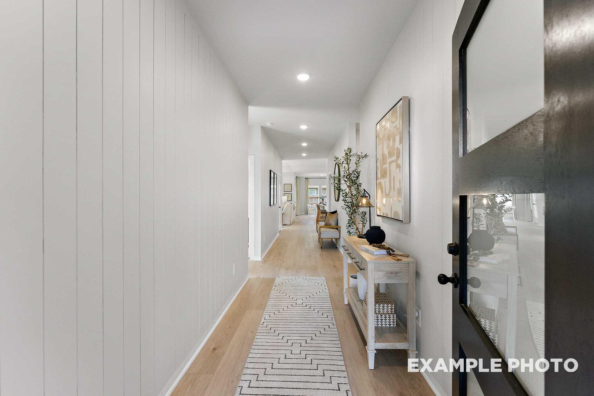 Spacious hallway in The Everett E home with white shiplap walls, hardwood floors, geometric rug, and modern console table