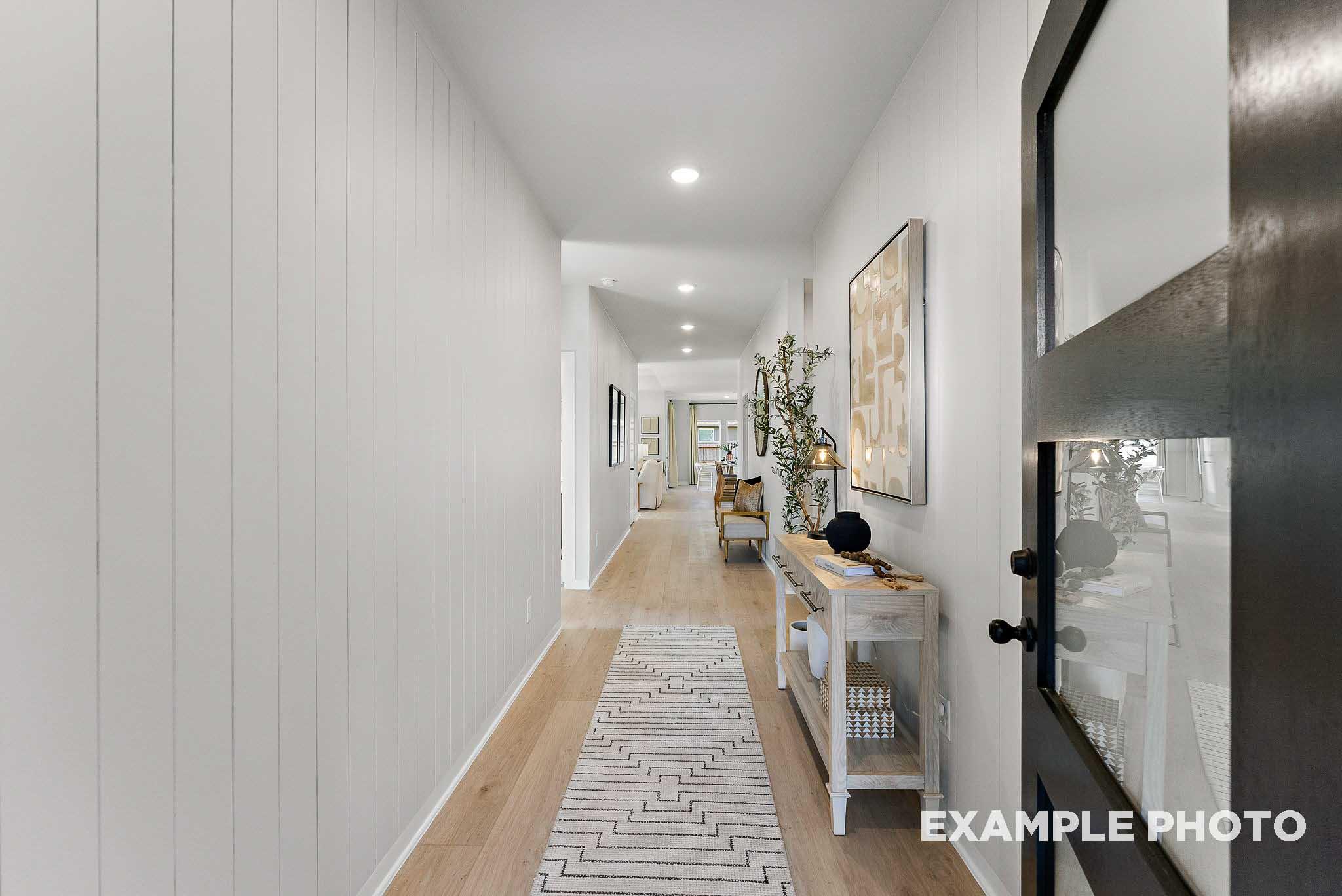 Bright, modern entryway with wood floors and shiplap wall in The Everett E floor plan by Davidson Homes in Crosby, Texas.