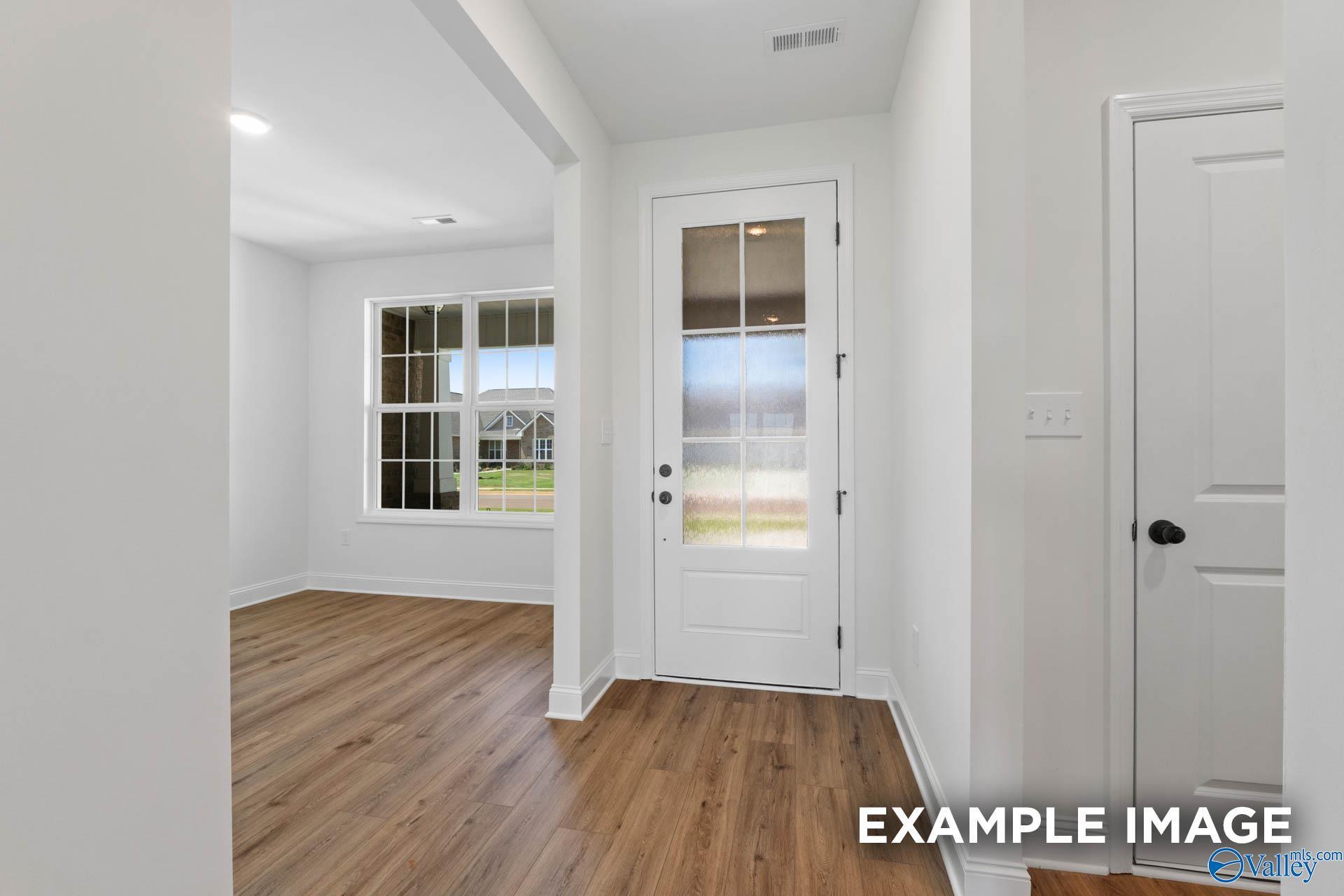 Bright foyer entry with glass-paneled front door and wood-look flooring in The Rockford B home at Briercreek, Meridianville.