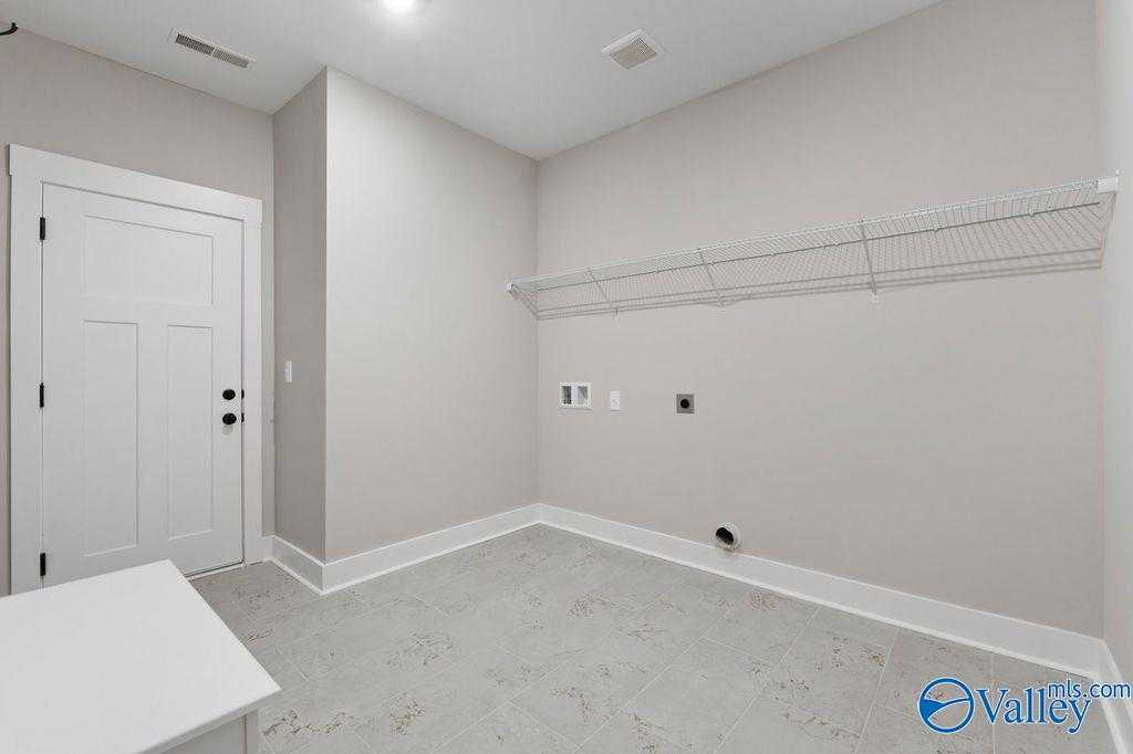 Functional laundry room featuring wire shelving, utility sink, washer/dryer hookups in 5-bedroom Evermore Homes The Oxford, Owens Cross Roads, AL