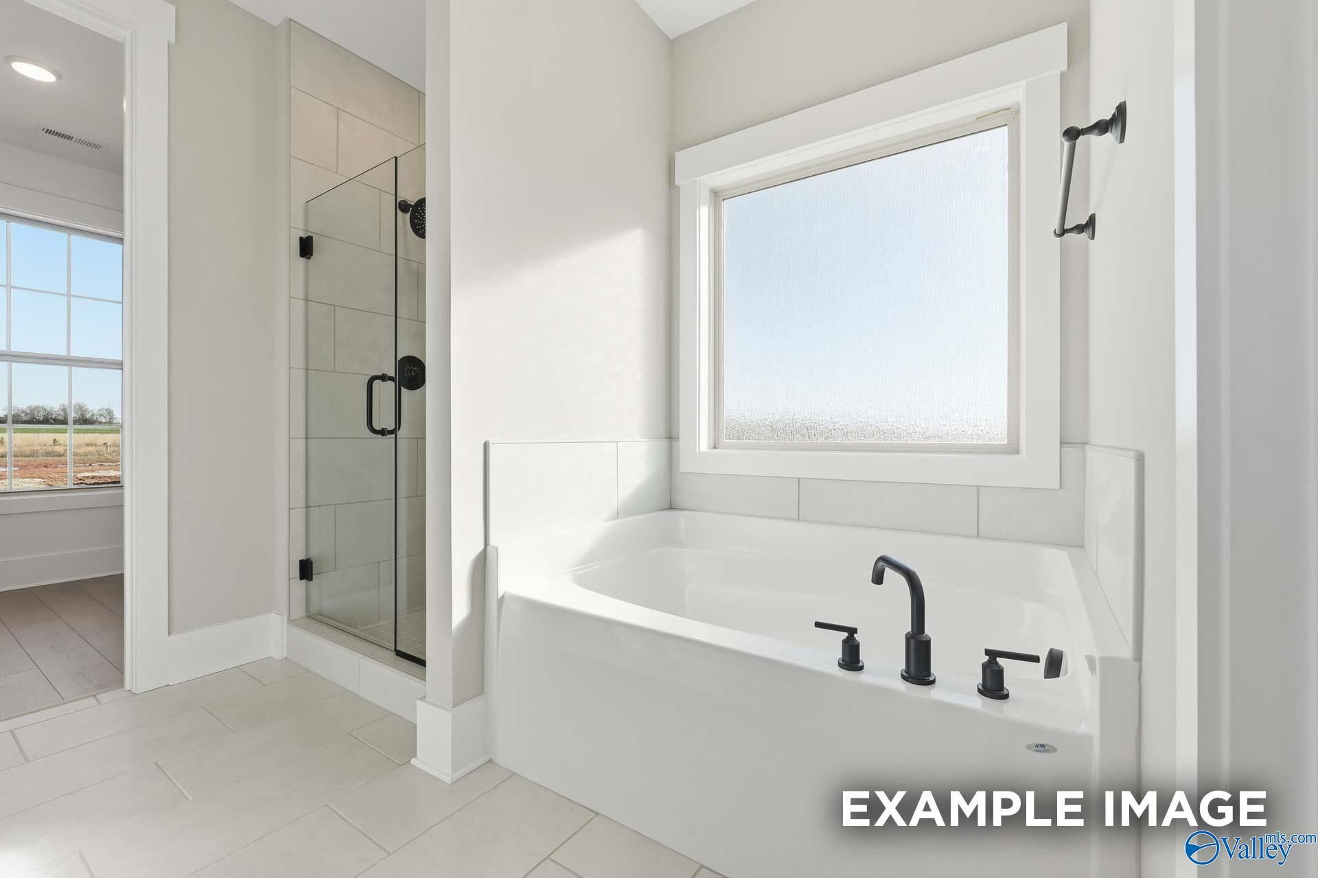 Luxurious master bathroom with freestanding tub, glass shower, and large windows in Davidson Homes The Emory, Decatur, Alabama