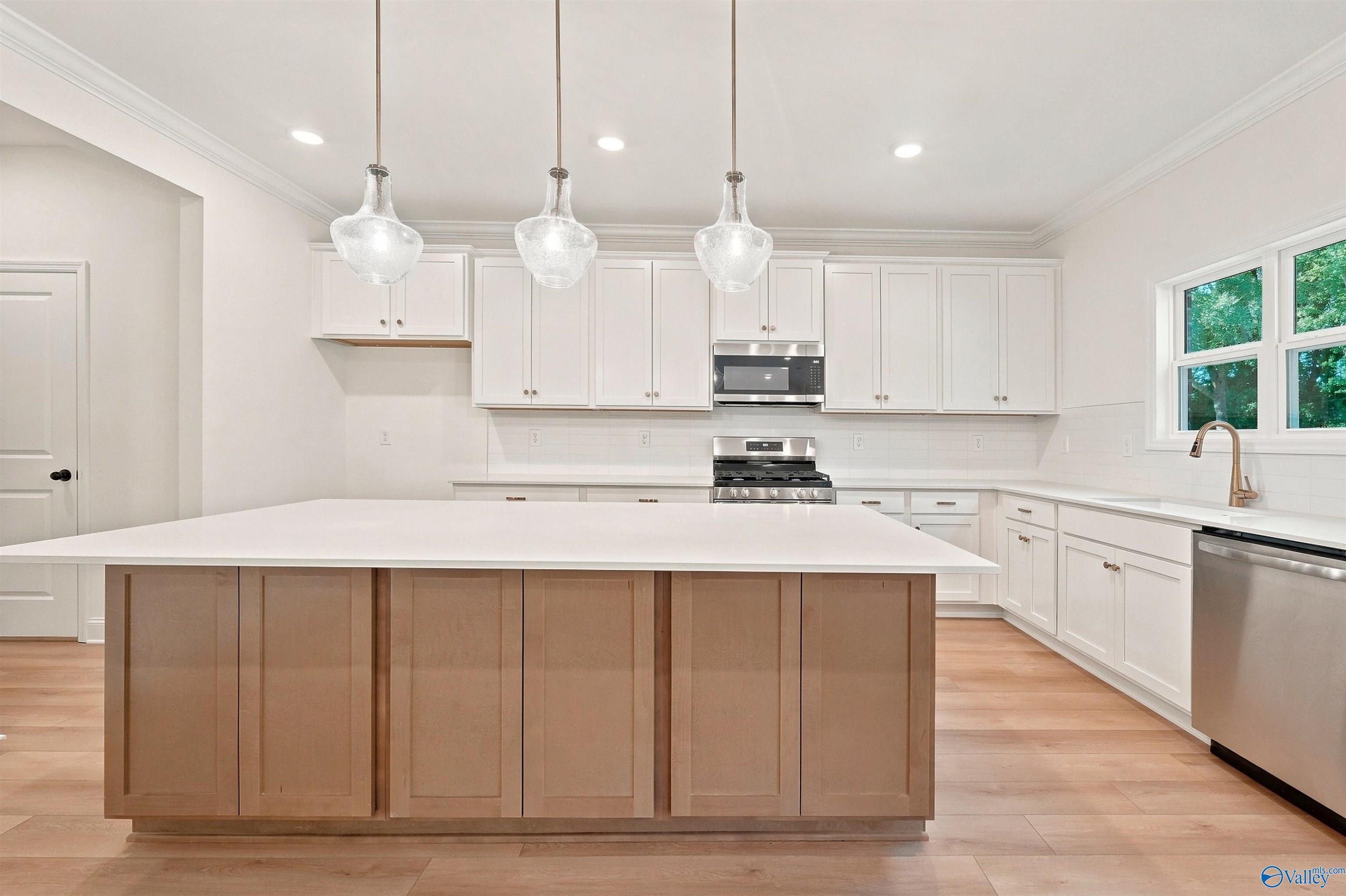 Modern white kitchen with large island and pendant lighting in The Chelsea C floor plan, Creek Grove, New Market, Alabama.