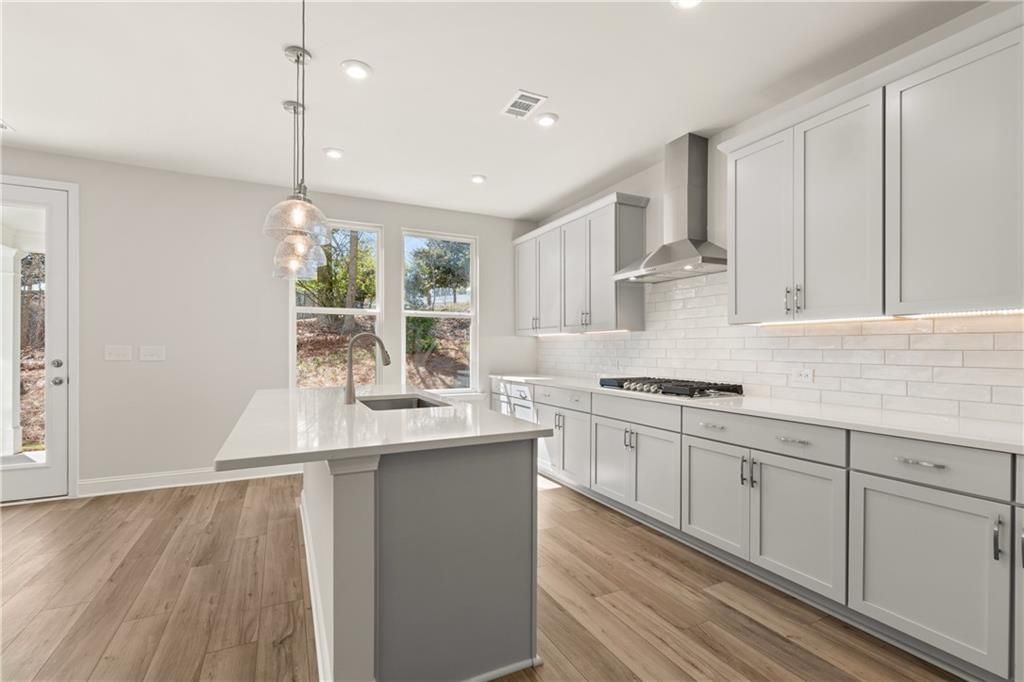 Modern kitchen with white quartz island, gray cabinets, subway tile backsplash, stainless appliances in The Danbury C, Buford, GA