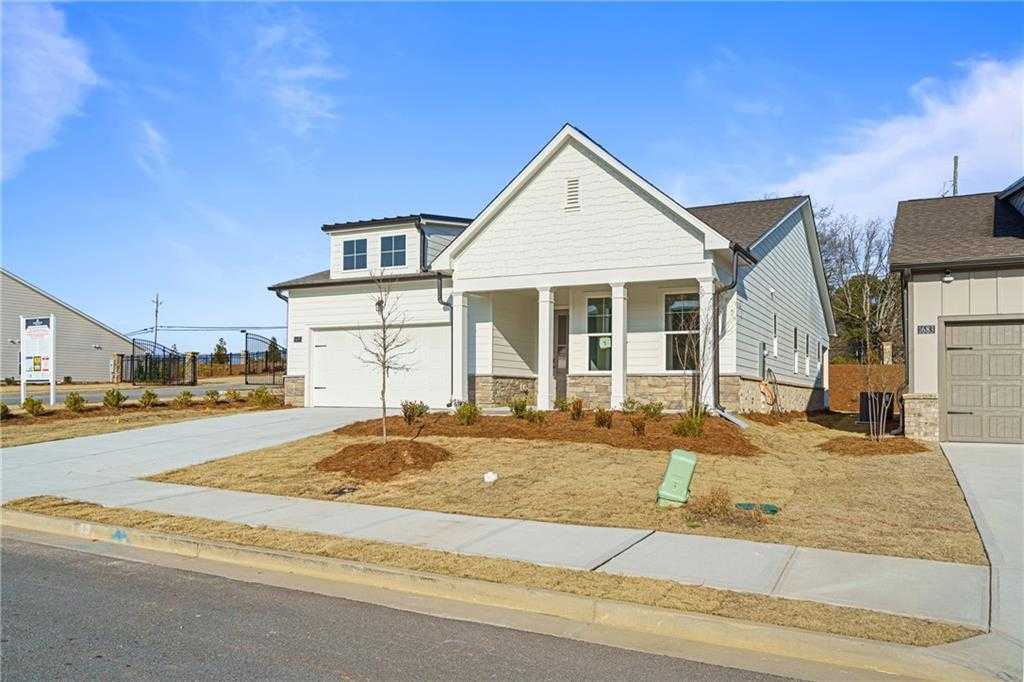 Modern white single-story home with gabled roof, front porch, 2-car garage, and for-sale sign in Kelly Preserve, Loganville, Georgia
