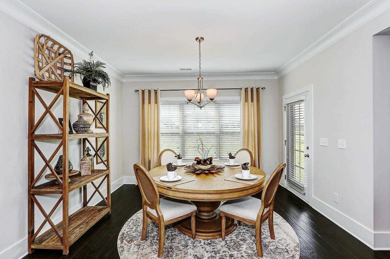 Spacious formal dining room in The Finleigh with round oak table, chandelier, wooden shelves, and large windows
