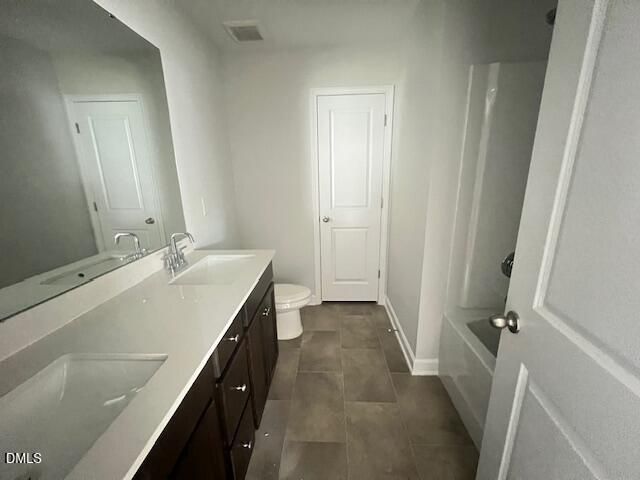 Modern master bathroom with double vanity, quartz countertop, soaking tub, and tile flooring in The Adalynn A, Lillington, NC