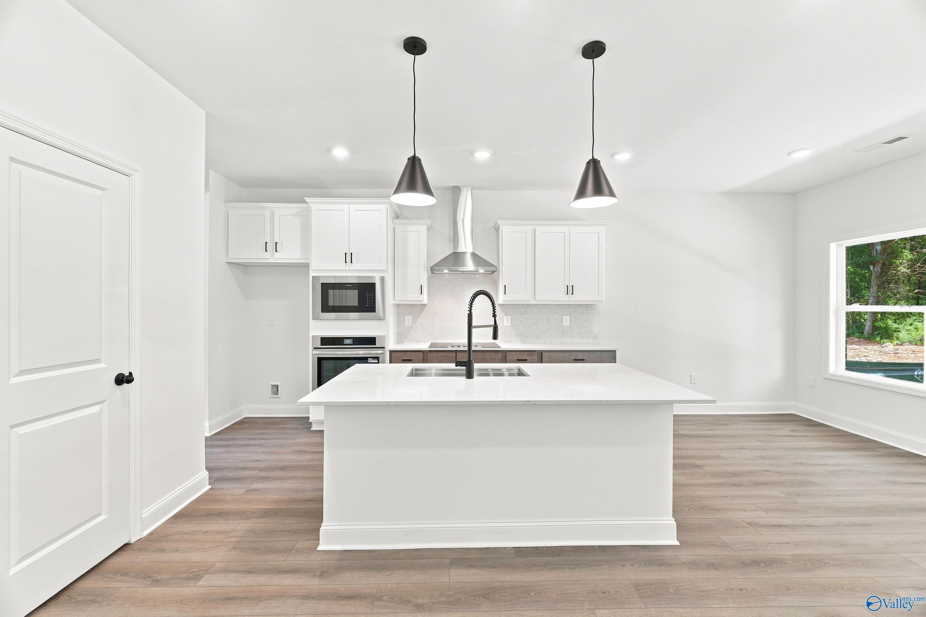 Modern kitchen with white island, quartz countertops, and stainless steel appliances in The Shelby B at Jaguar Hills.