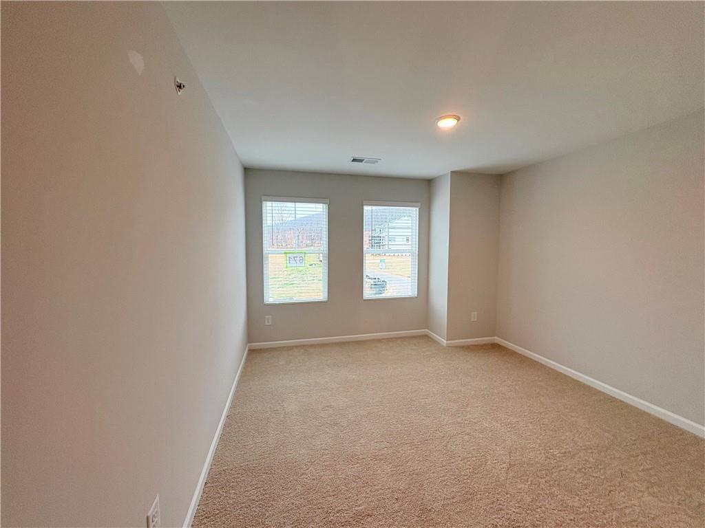 Empty bedroom with beige carpet, light gray walls, and double windows in Davidson Homes The Wake E, Cumming, Georgia