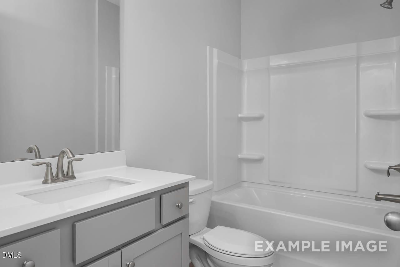 Modern bathroom with white bathtub shower combo, gray vanity sink, and toilet in Davidson Homes Adalynn A, Lillington NC