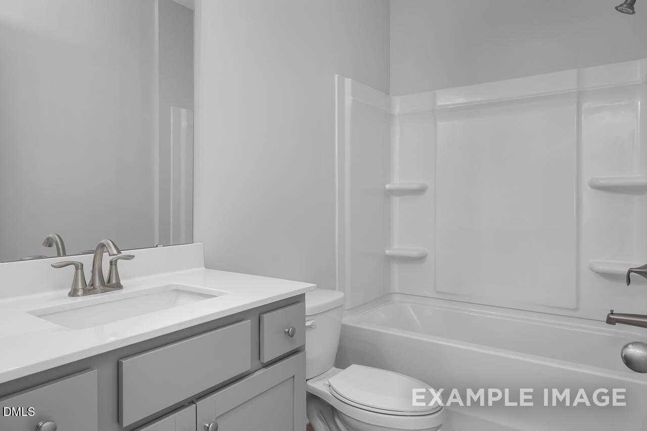 Modern bathroom with white bathtub shower combo, gray vanity sink, and toilet in Davidson Homes Adalynn A, Lillington NC