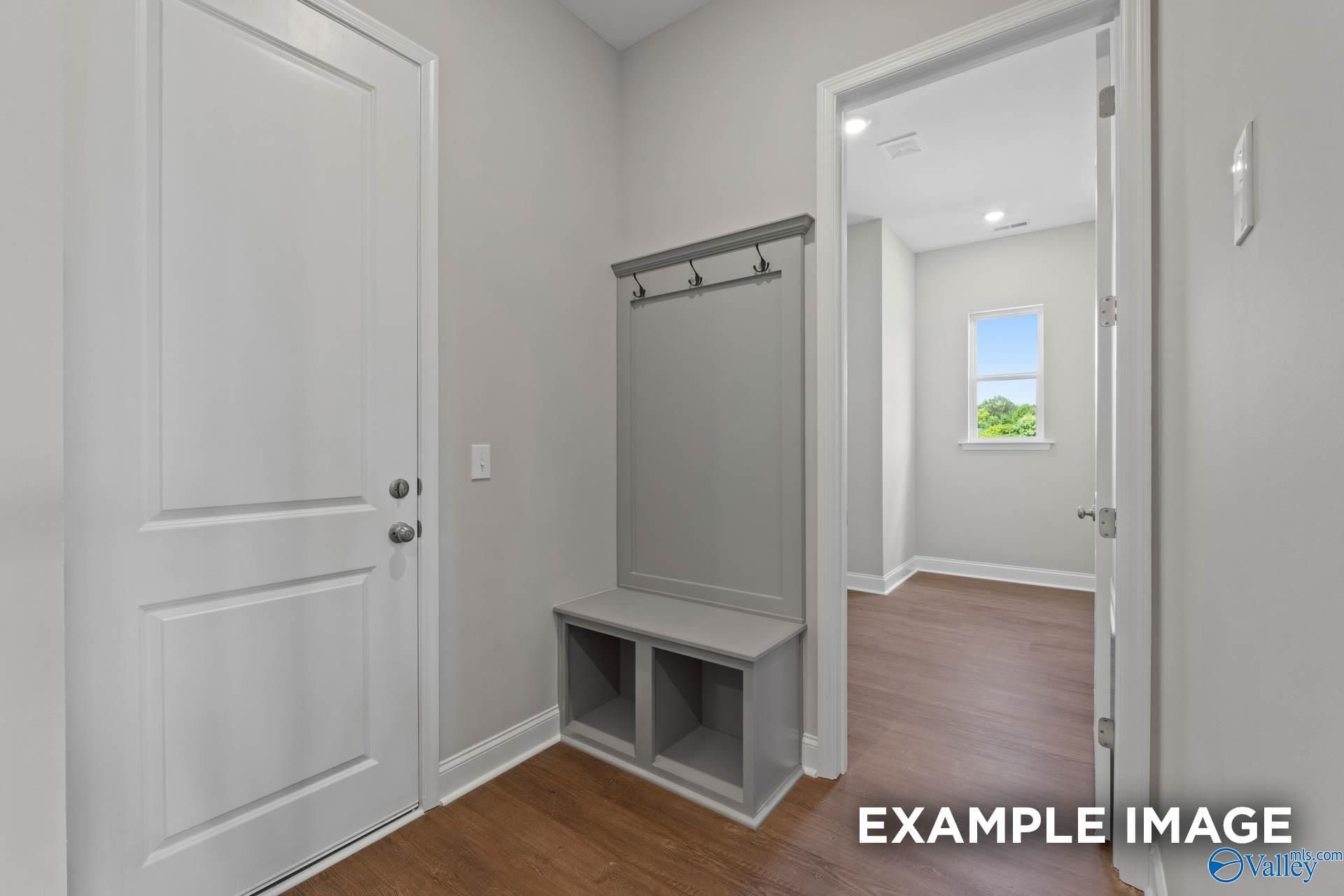 Functional mudroom with built-in gray bench, coat hooks, and storage cubbies in Evermore Homes The Arcadia, Owens Cross Roads, Alabama