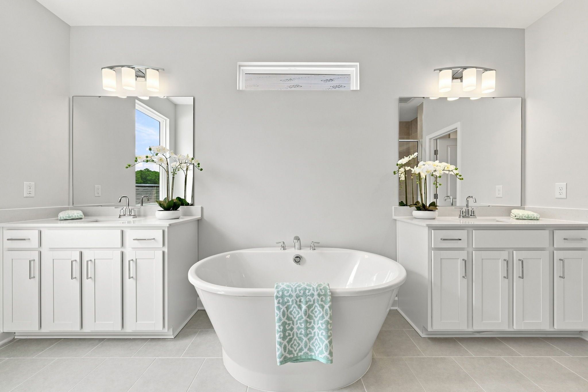 Spacious master bathroom in The Jordan A featuring a freestanding soaking tub and dual vanities with white cabinetry.