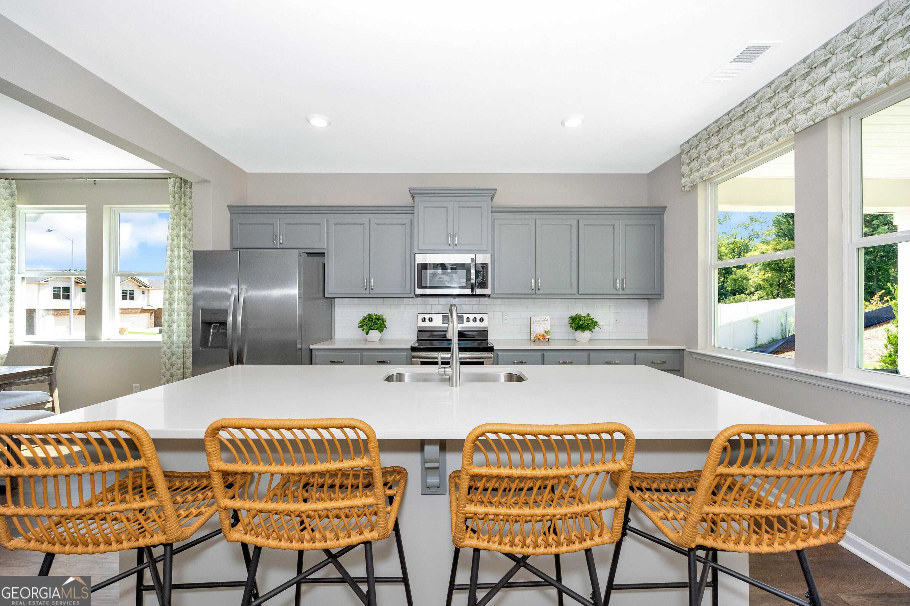 Modern kitchen with gray cabinets, stainless steel appliances, and spacious island in The Stella 4-bedroom home, Perry, Georgia