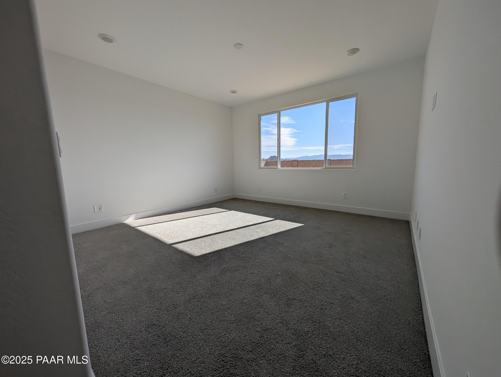 Sunlit empty bedroom with large window showcasing mountain views in The Sheridan II F, Prescott, Arizona home