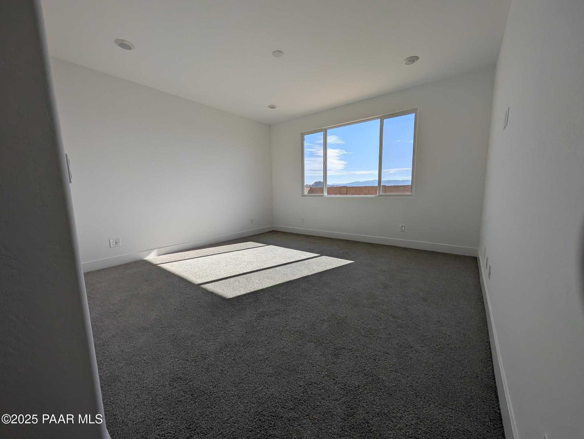 Sunlit empty bedroom with large window showcasing mountain views in The Sheridan II F, Prescott, Arizona home