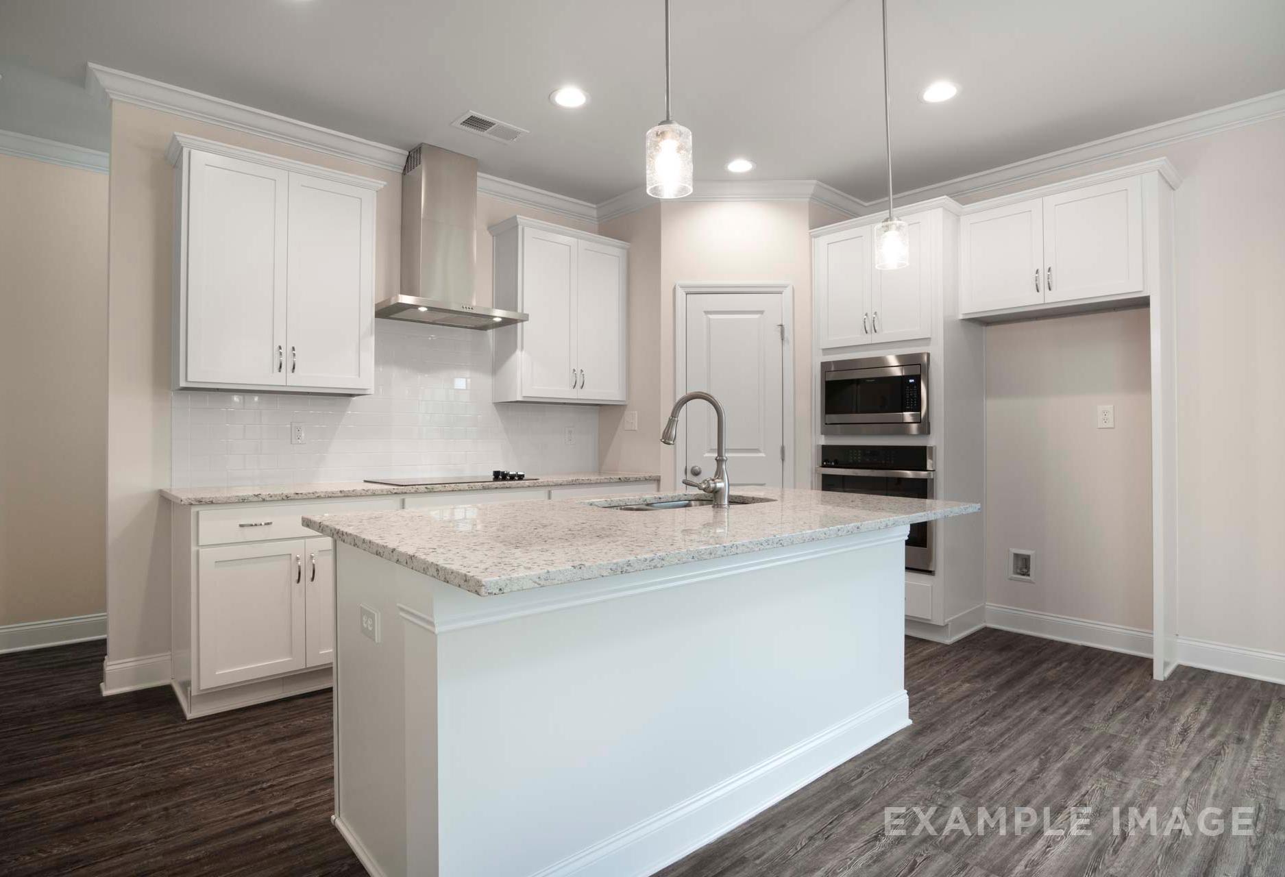 Modern kitchen in The Charleston with white shaker cabinets, granite center island, double wall ovens, and pendant lights