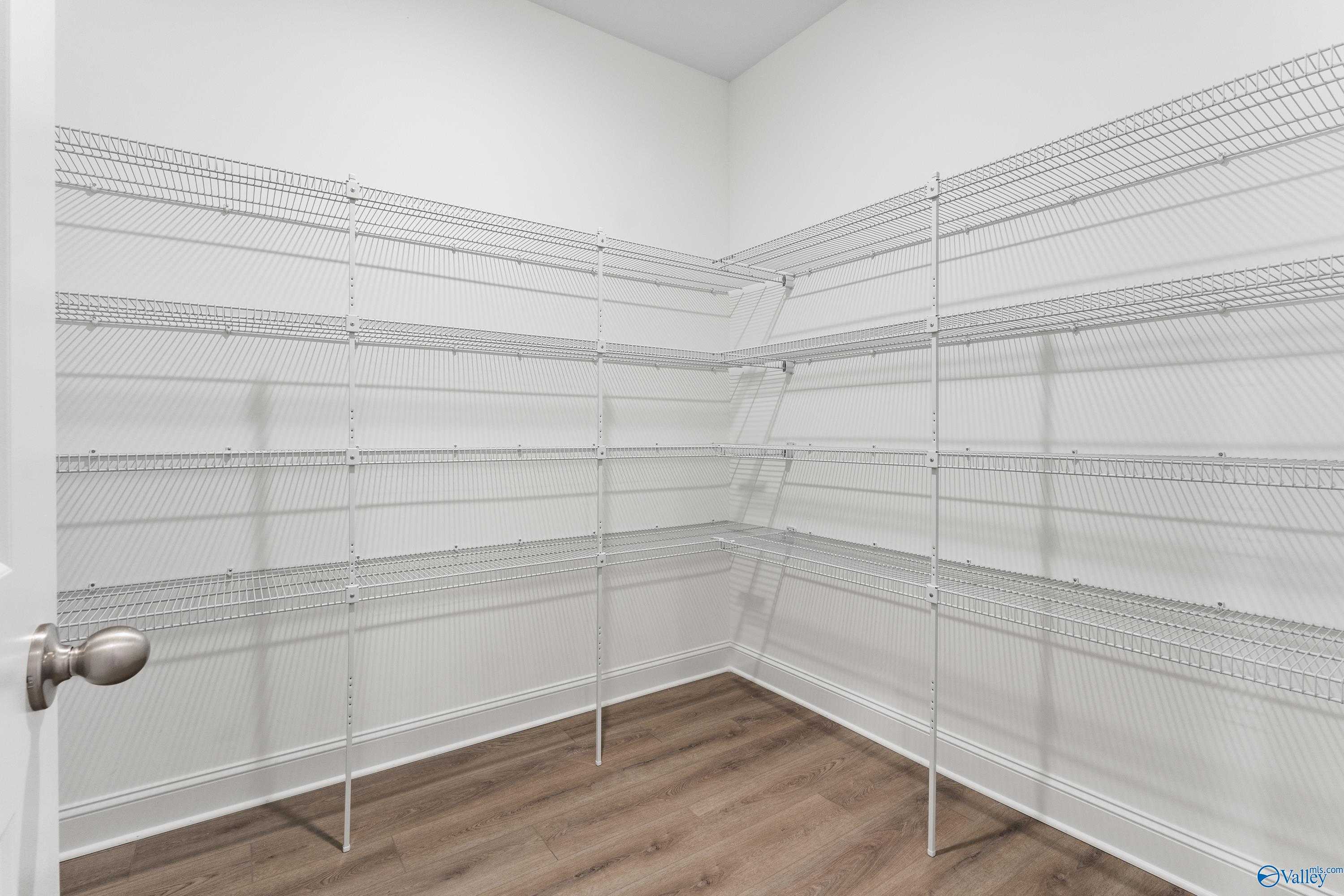 Spacious walk-in closet with wire shelving and luxury vinyl plank flooring in The Finleigh home, Toney, Alabama