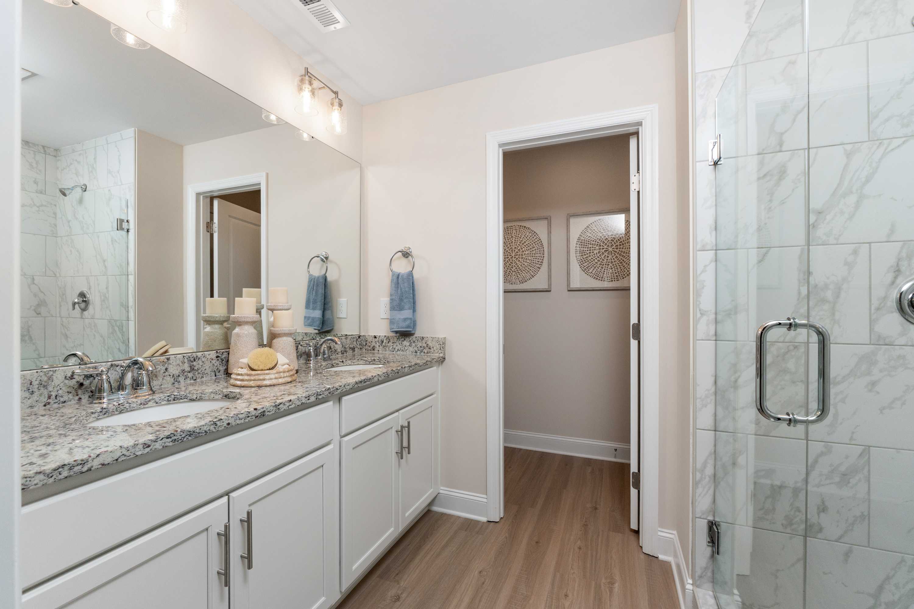 Spacious master bathroom at Pavilion in Huntsville Alabama with double granite vanity frameless glass shower and hardwood floors