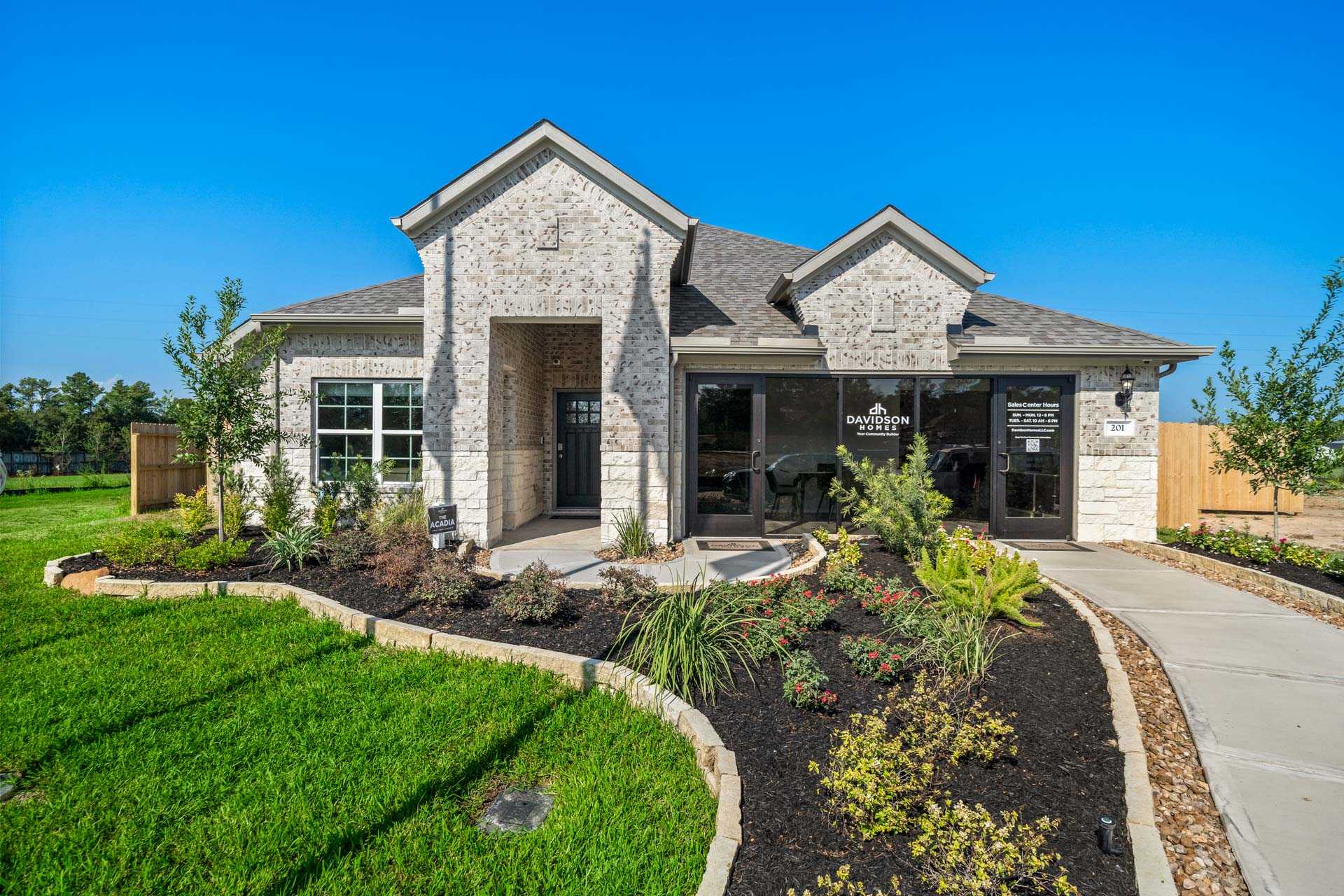 Modern brick home exterior at Windmill Estates in Magnolia Texas with gabled roof, large windows, and landscaped pathway