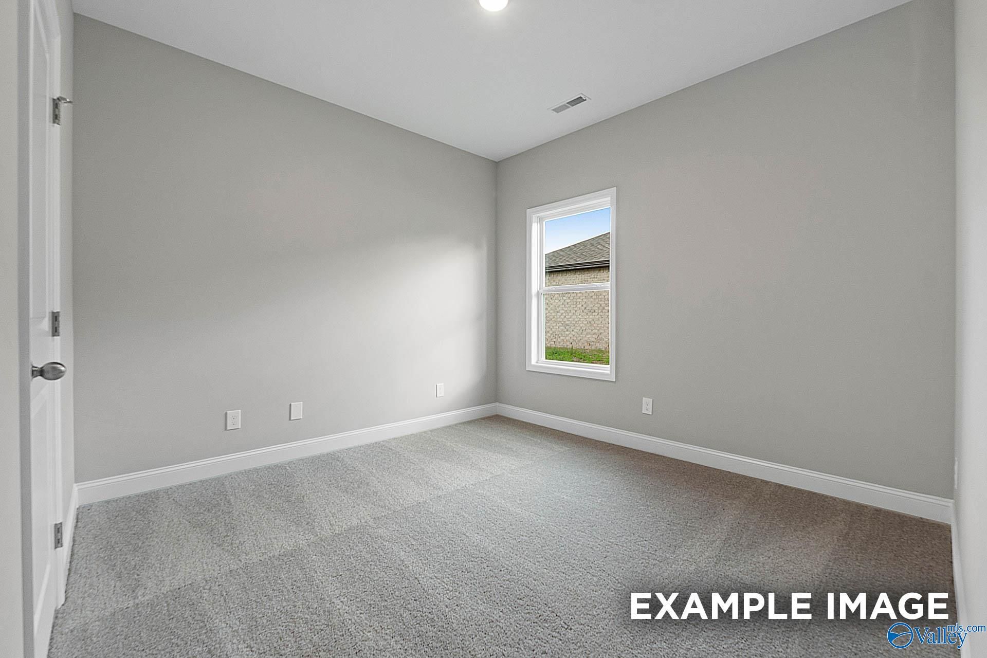 Spacious empty bedroom with gray walls, plush carpet, and window view in Davidson Homes The Franklin E, Hazel Green, AL