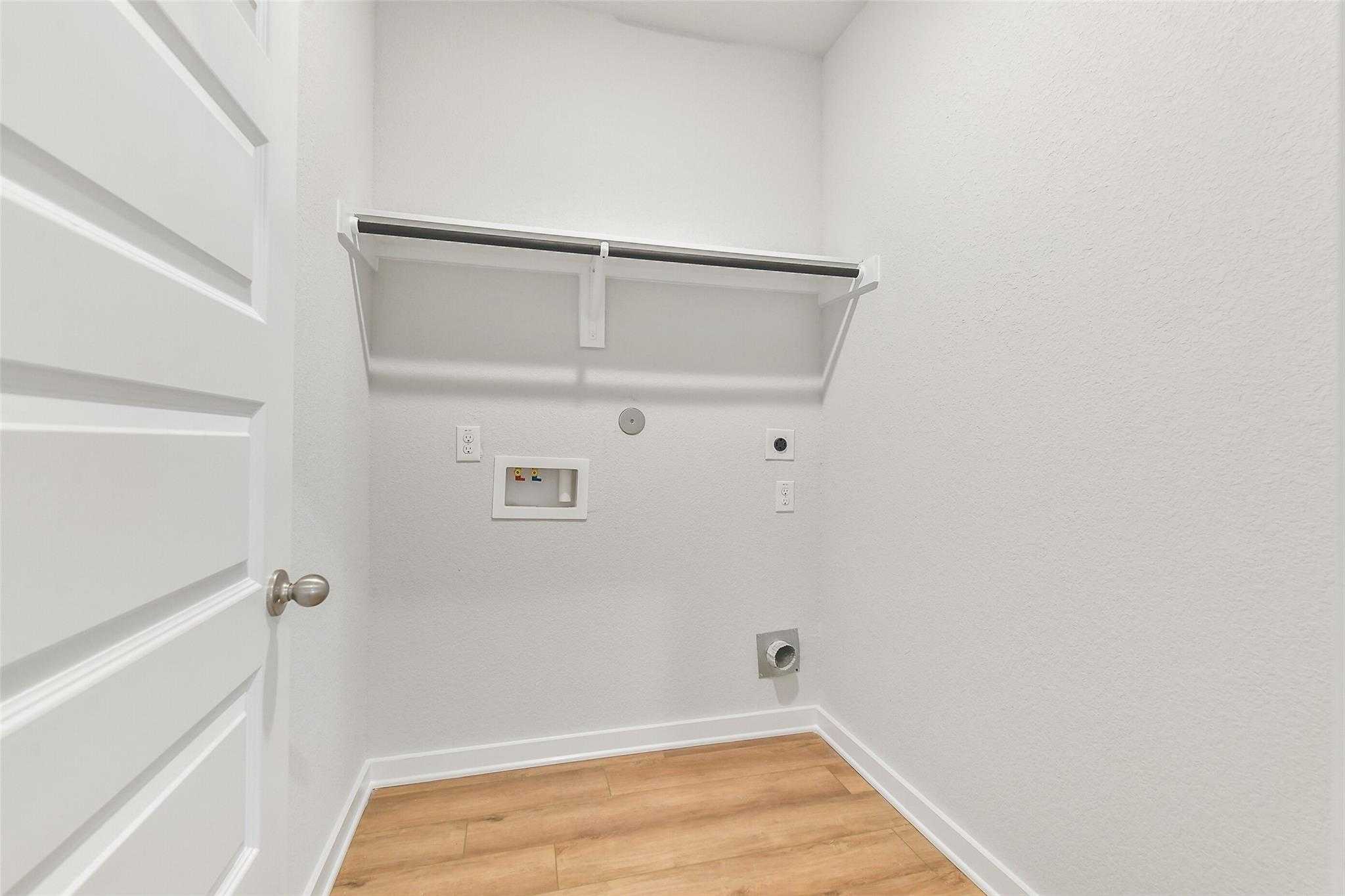 Spacious laundry room with washer-dryer hookups, storage closet and laminate flooring in Davidson Homes The Blanco E, Magnolia TX