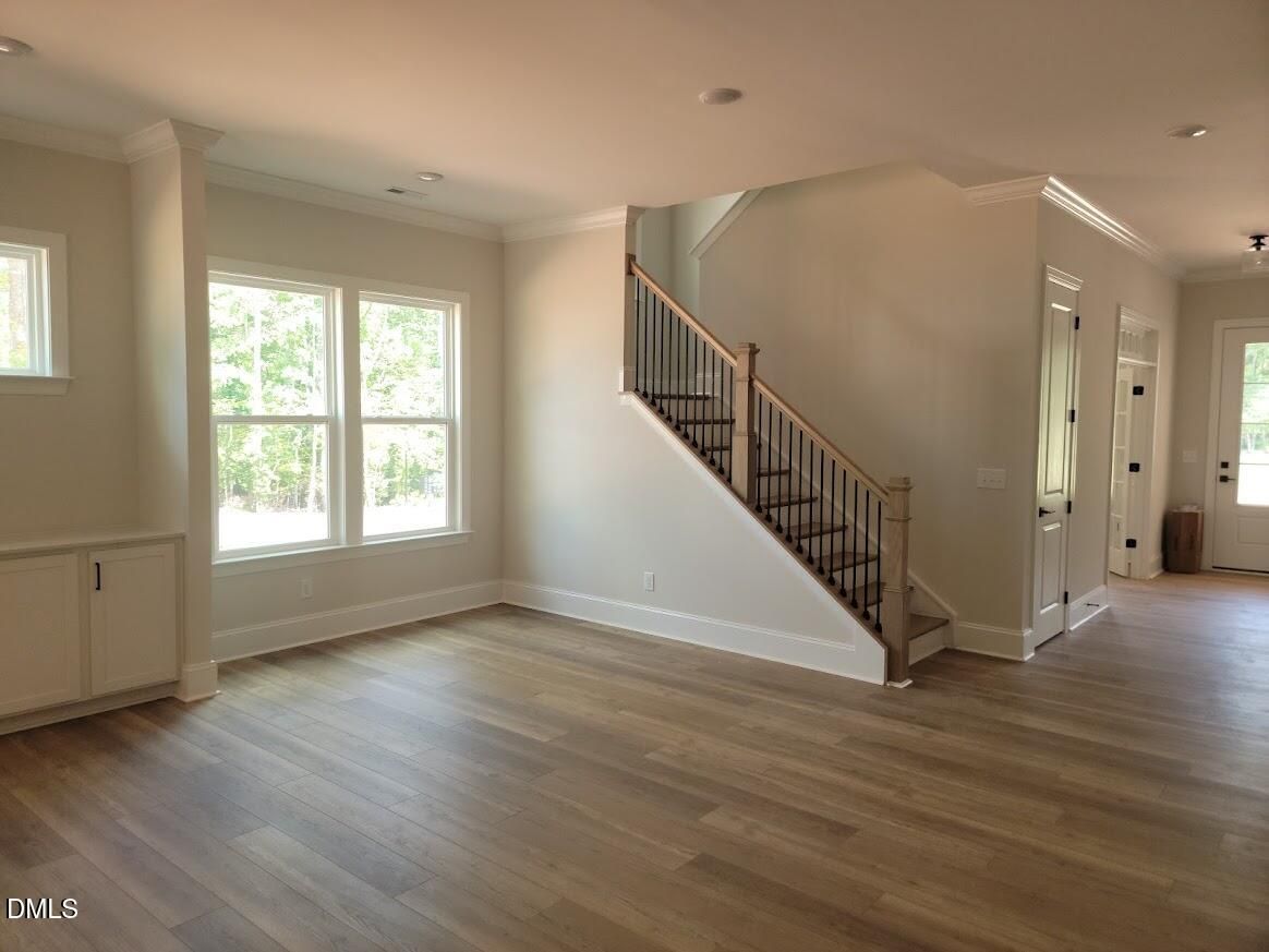 Bright open living area with hardwood floors, staircase with iron balusters, and large windows in Davidson Homes' Magnolia II B, Wake Forest, NC