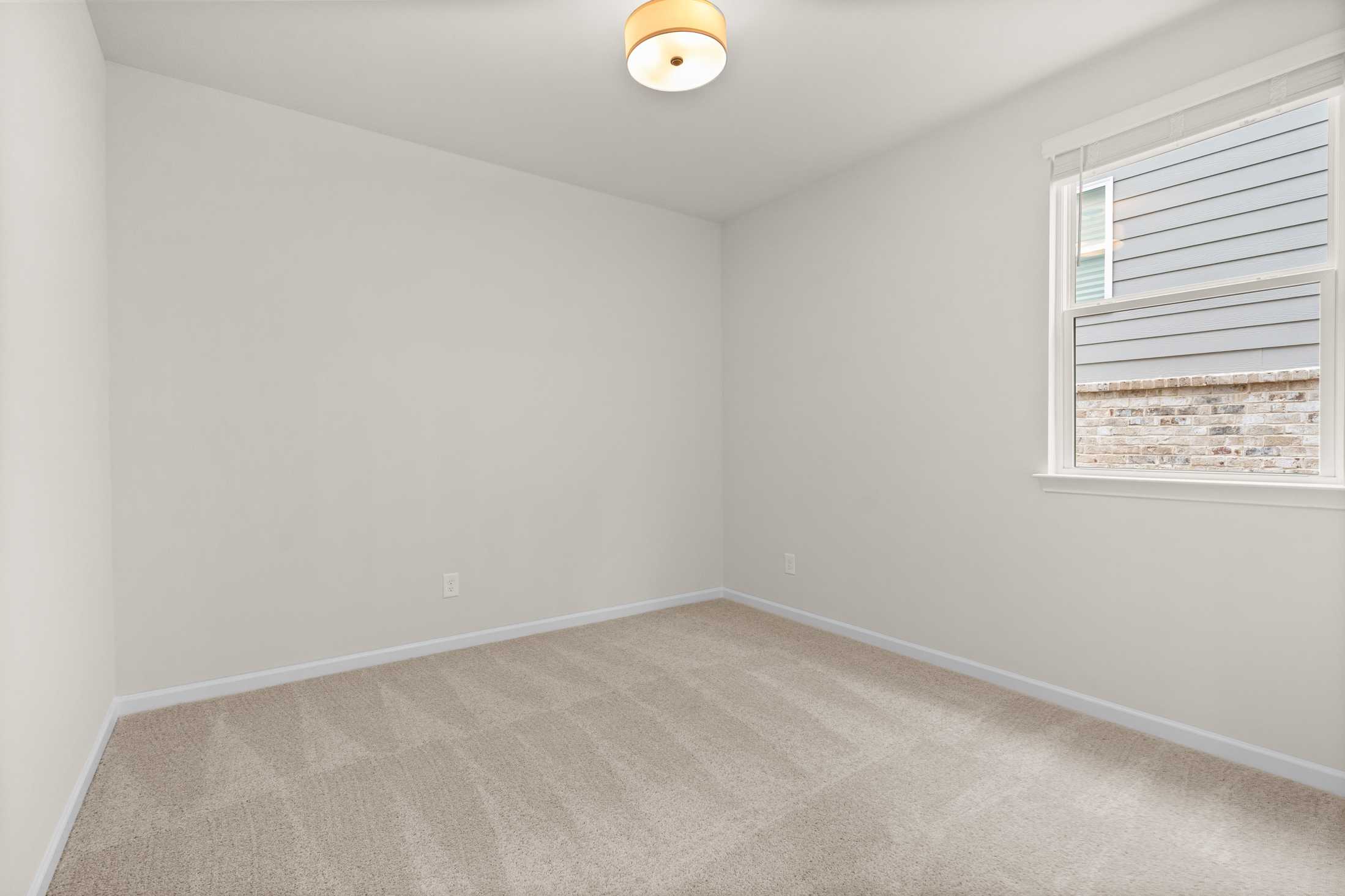 Spacious empty bedroom in The Glenwood B by Davidson Homes, featuring neutral walls, beige carpet, ceiling light, and large window