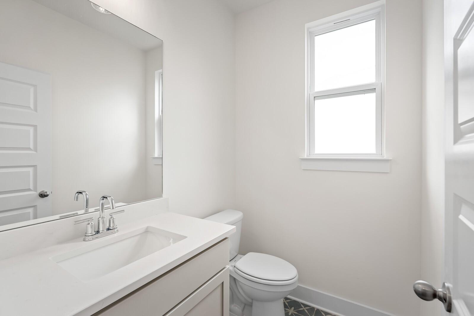 Modern half bathroom with white shaker vanity, undermount sink, mirror, and toilet in Davidson Homes The Ridgeport, Gallatin, TN