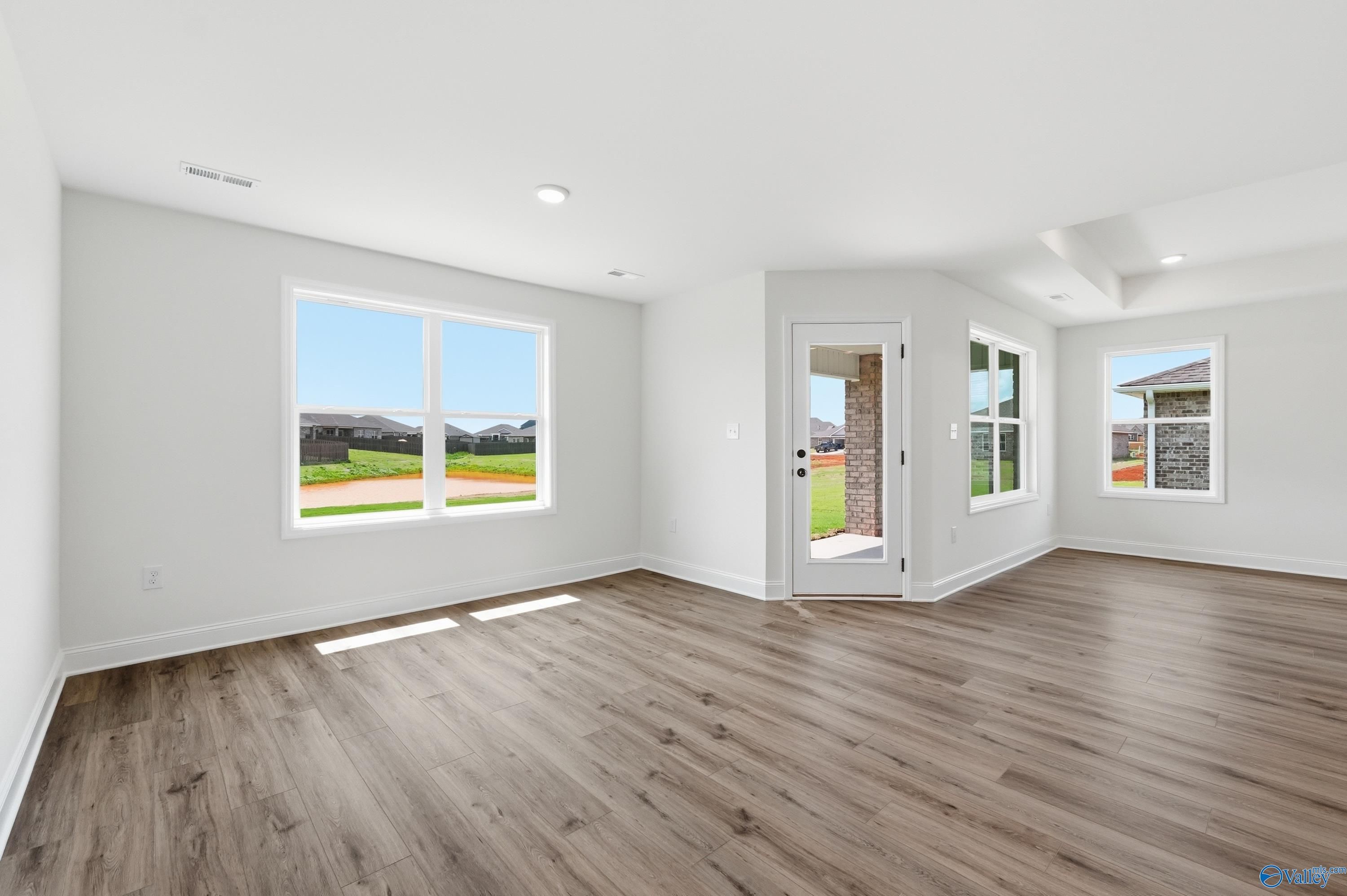 Bright open-concept living area with wood-look flooring and backyard access in The Franklin at Heritage Lakes, New Market.