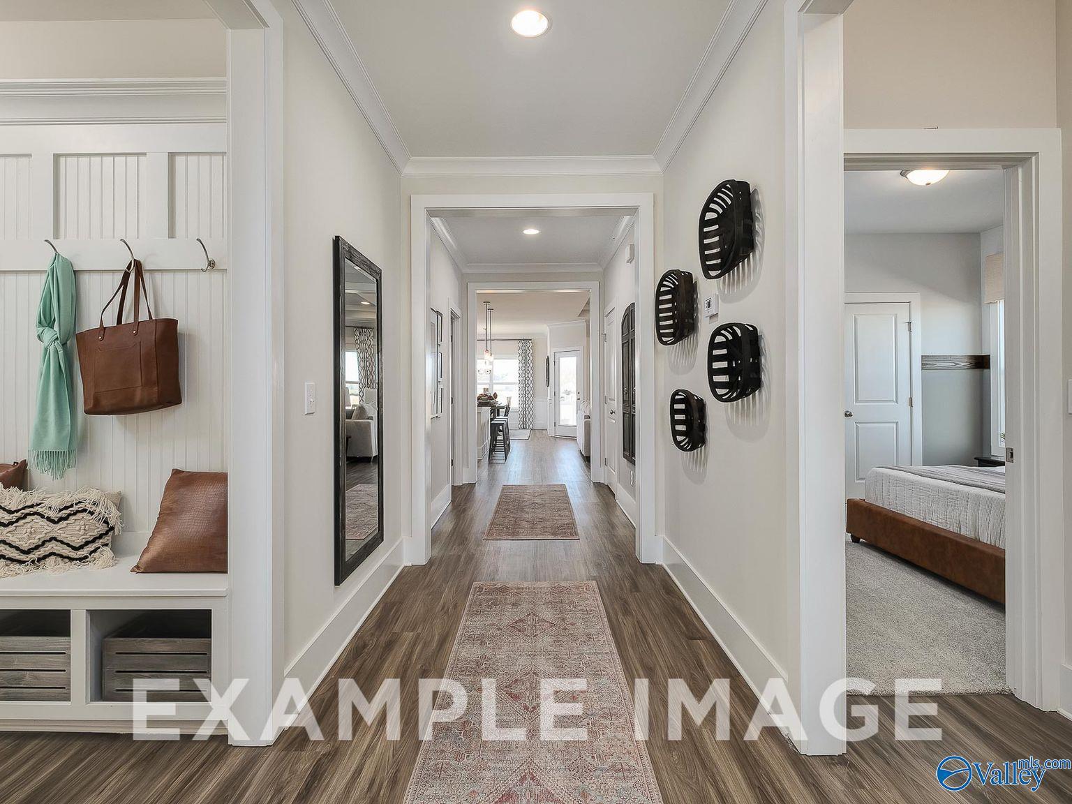 Elegant hallway with wood floors, Persian runner rug, coat bench, purse, mirror, and art in Davidson Homes The Everett B, Toney, AL